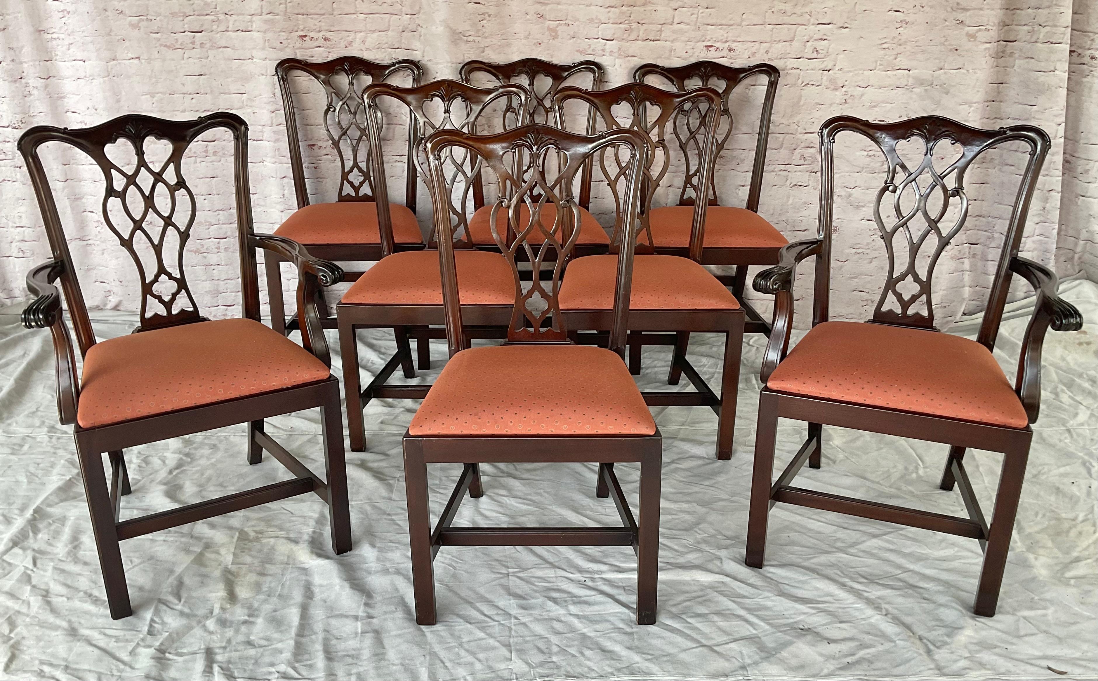 20th Century Set of Eight Chippendale-Style Mahogany Dining Chairs. There are two armchairs and six side chairs. Chairs feature intricately carved backs, a sturdy frame, and upholstered slip seats. The pierced splats feature interlacing ribbon