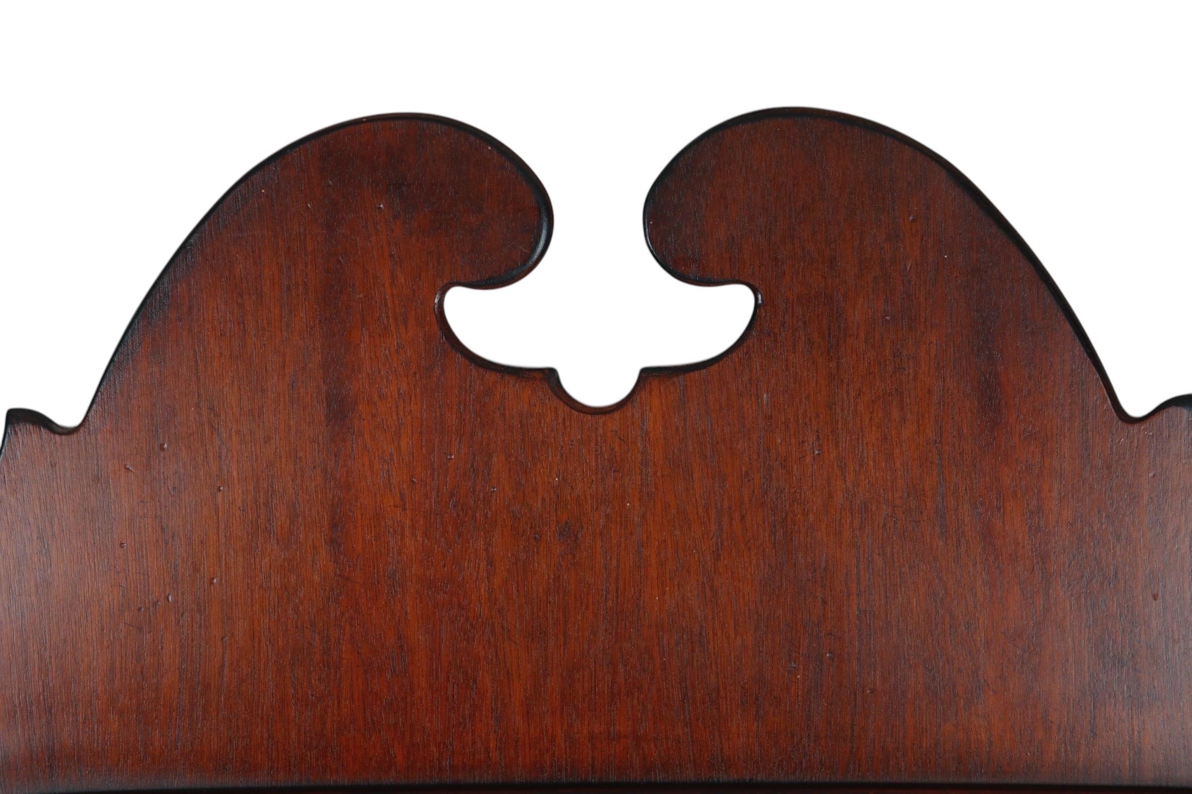 A Chippendale style wall mirror in mahogany by Drexel Heritage, made for their Collectors Collection. The mirror has a serpentine beveled edge that follows the serpentine inner carved edge of the frame. Above is decorated with a broken pediment