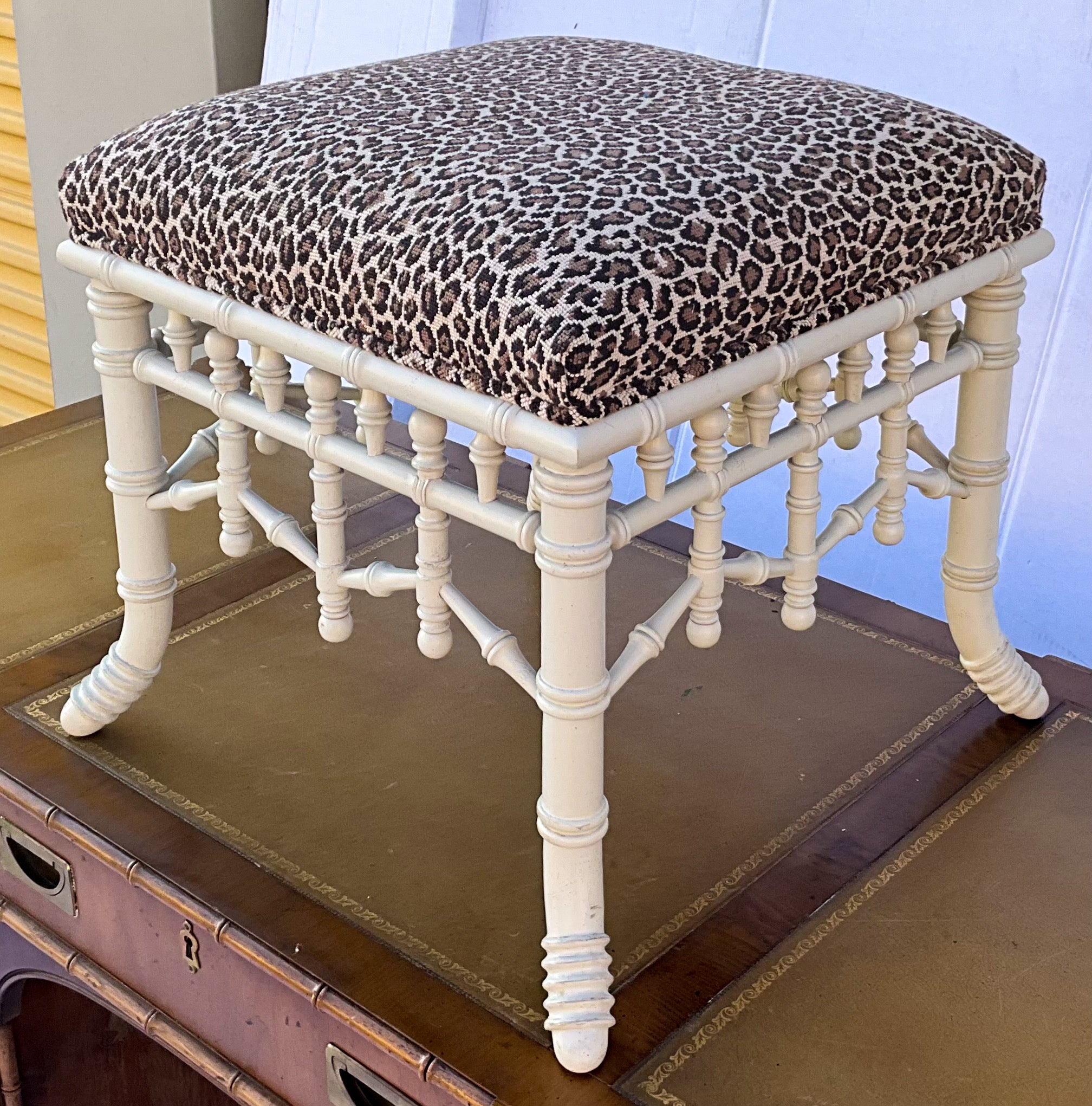 This is a French Chippendale style painted faux bamboo ottoman with a leopard needlepoint. It is unmarked and in very good condition.