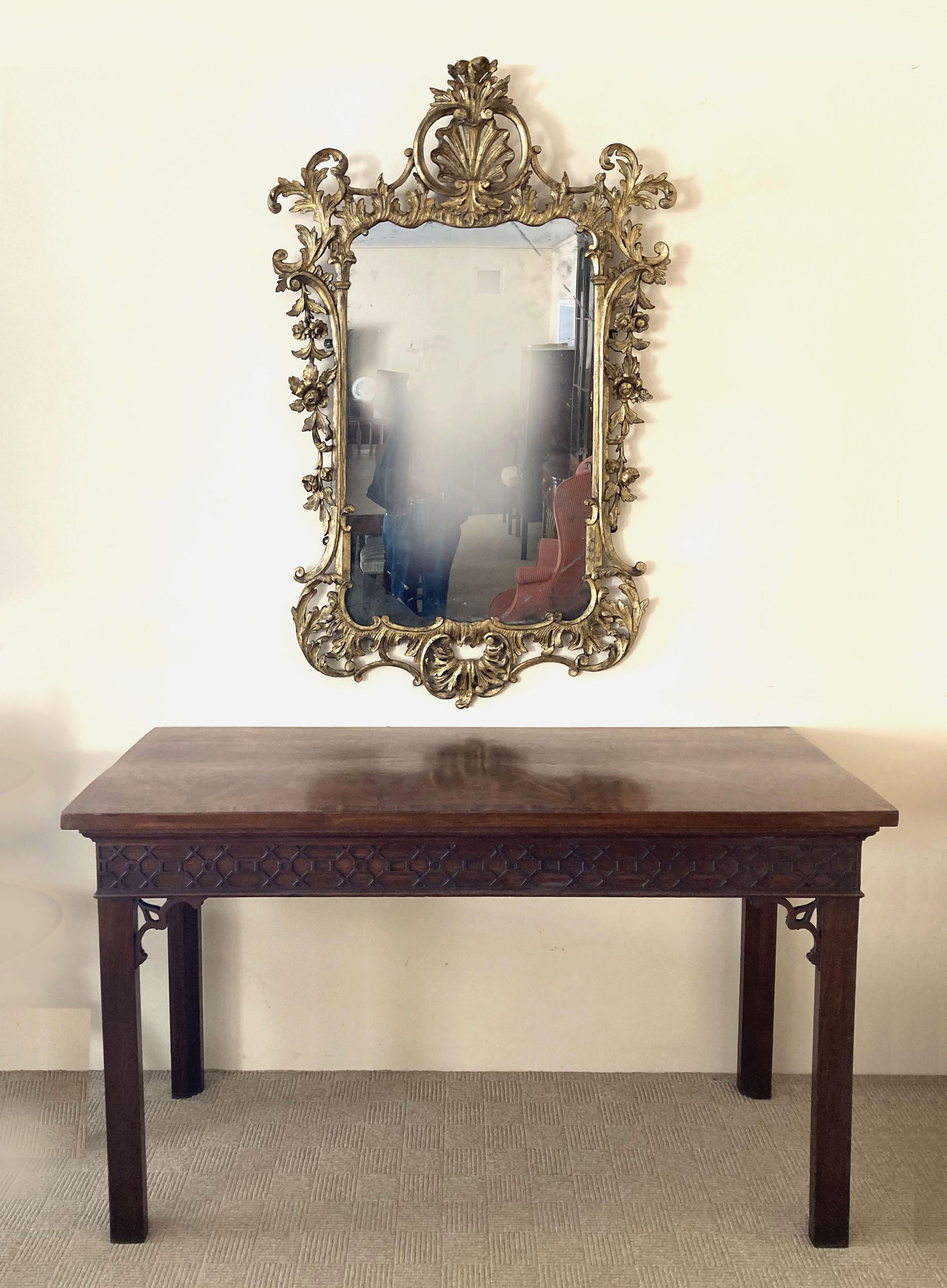 A fine early 19th century carved mirror in its original gilt. The intricate giltwood frame showcases the finest craftsmanship of the period, featuring ornate carvings of flowers, shells, rococo scrolls, acanthus leaves and a beautifully aged patina.