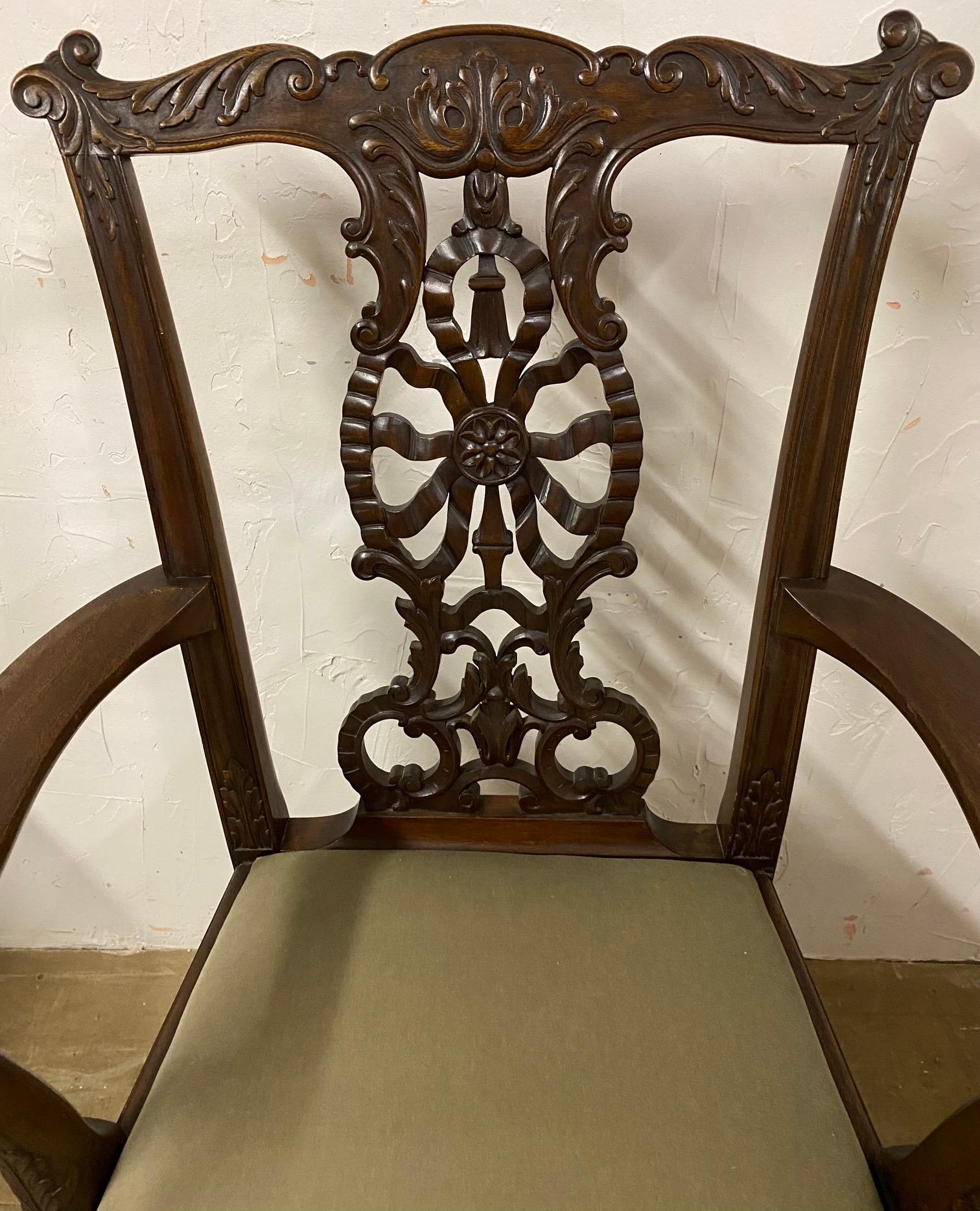 Ce fauteuil en acajou de style Chippendale, datant d'environ 1900, présente des motifs sculptés à la main, notamment un dossier combinant un motif de rubans, une rosette, une houppe et des feuilles. Les bras se terminent par des têtes d'aigle