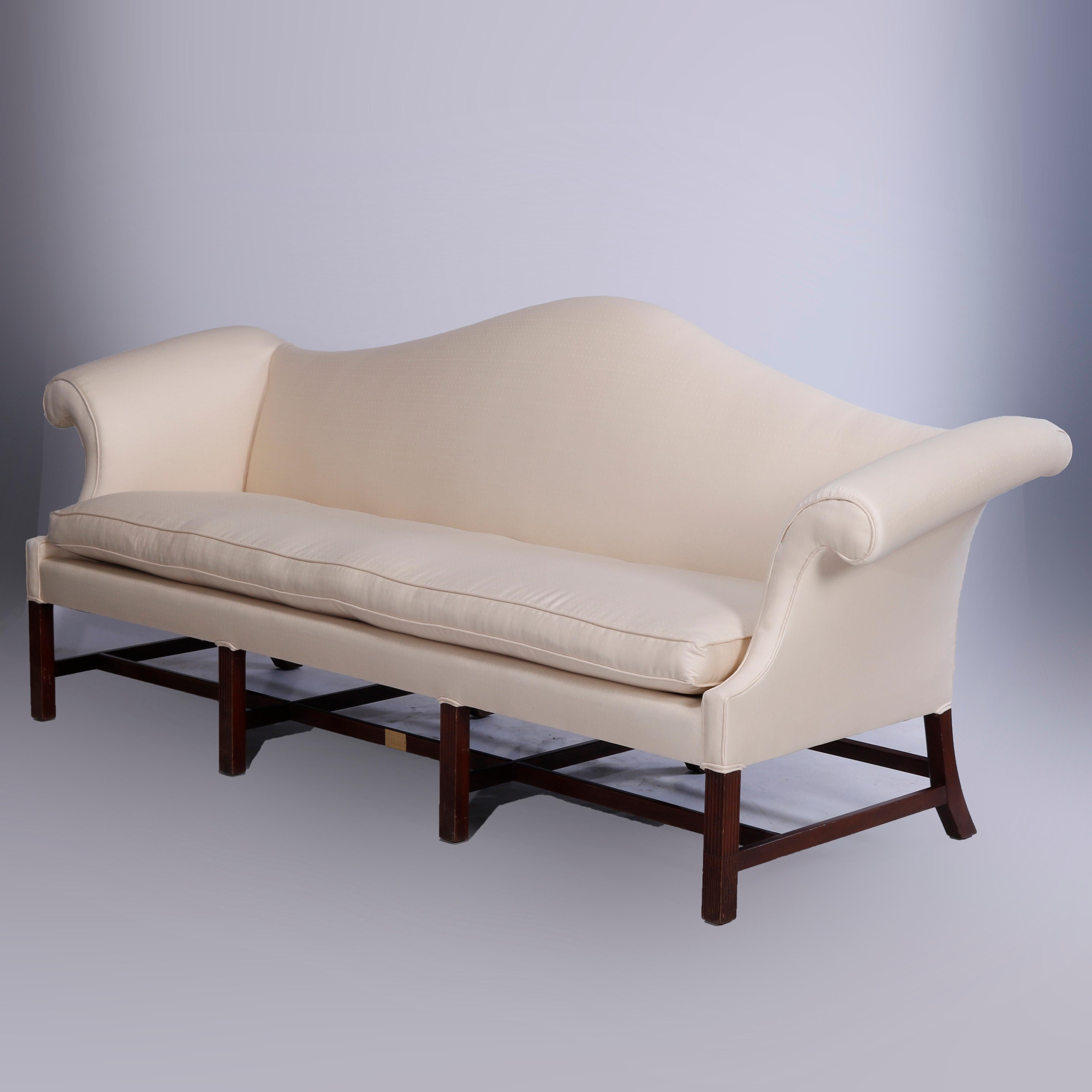 A Chippendale style sofa by Kittinger offers camel back form with scroll arms and raised on eight mahogany legs, maker label as photographed, c1950

Measures - 39.5'' H x 96.5'' W x 34.5'' D; SH: 20''.