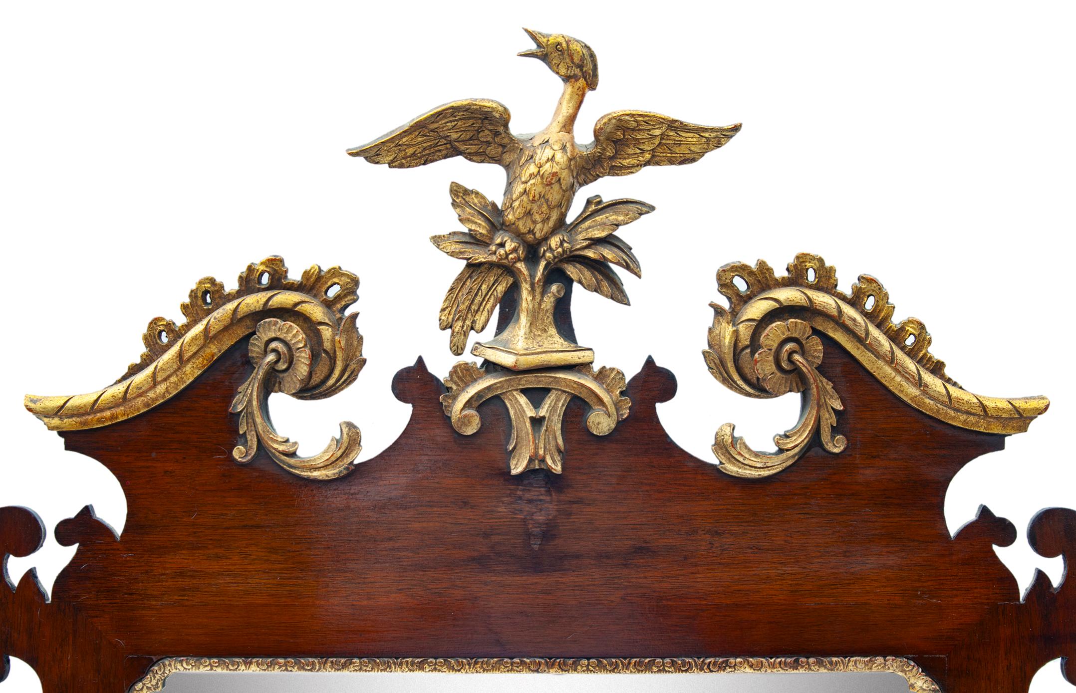 A stunning mahogany and giltwood mirror having highly detailed carvings & a dramatic pediment adorned with a Phoenix. There is a wonderful hand carved and gilt Eagle/Phoenix at the top of the mirror. The mirrored glass and backboard are original.