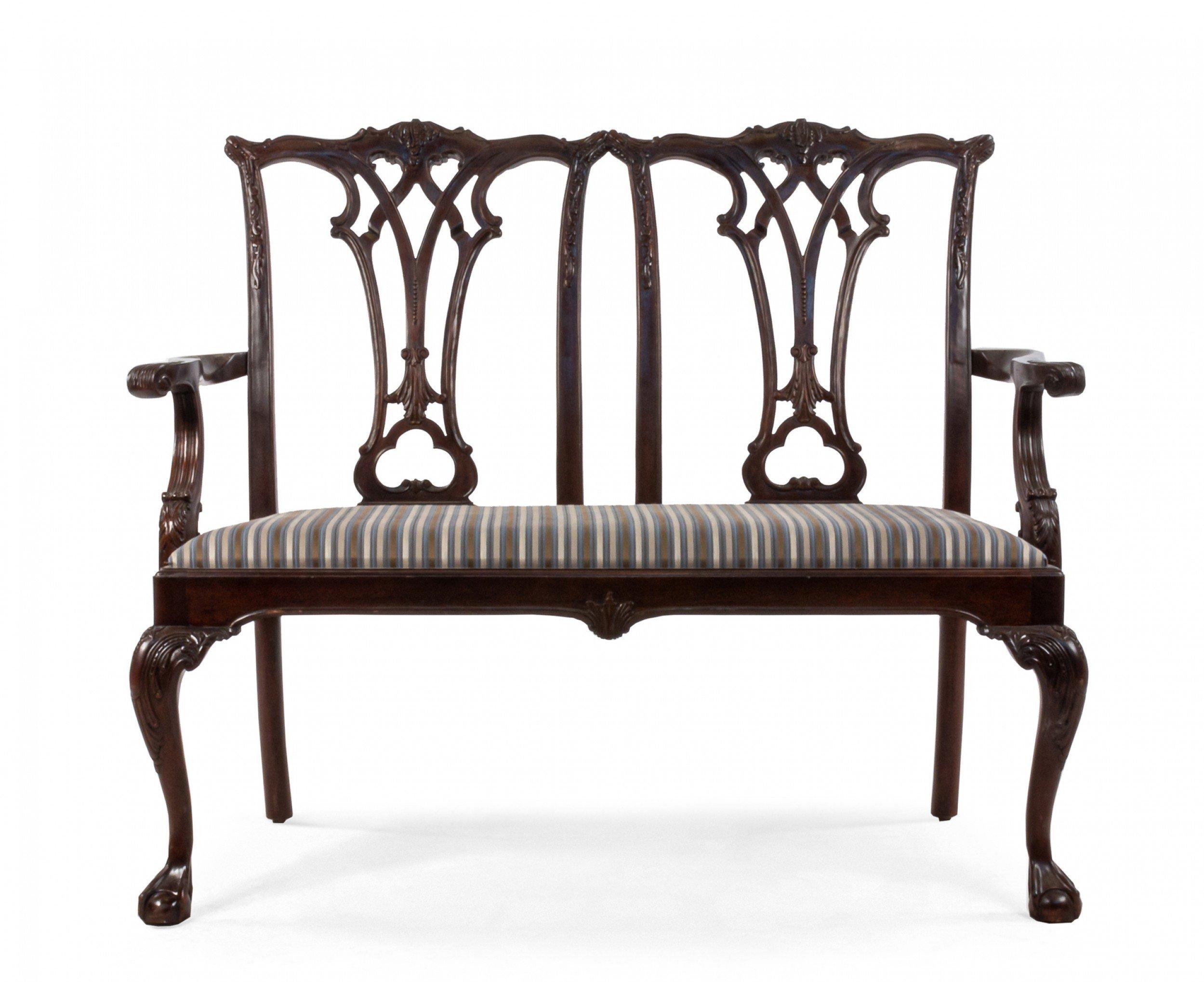 English Chippendale style (late 19th Century) mahogany loveseat with open carved double chair back having beige and blue striped upholstered seat supported on cabriole legs with ball and claw feet.