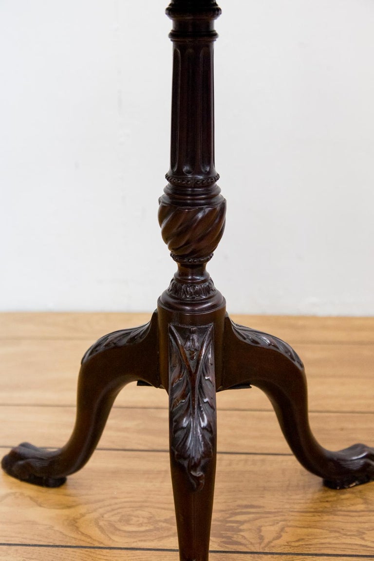 Chippendale style needlework tripod table has a floral needlework under glass. The stem is fluted with a spiral knop. It has bell flower and acanthus carved legs terminating in hairy paw feet. The top edge has gadrooned carving.


   