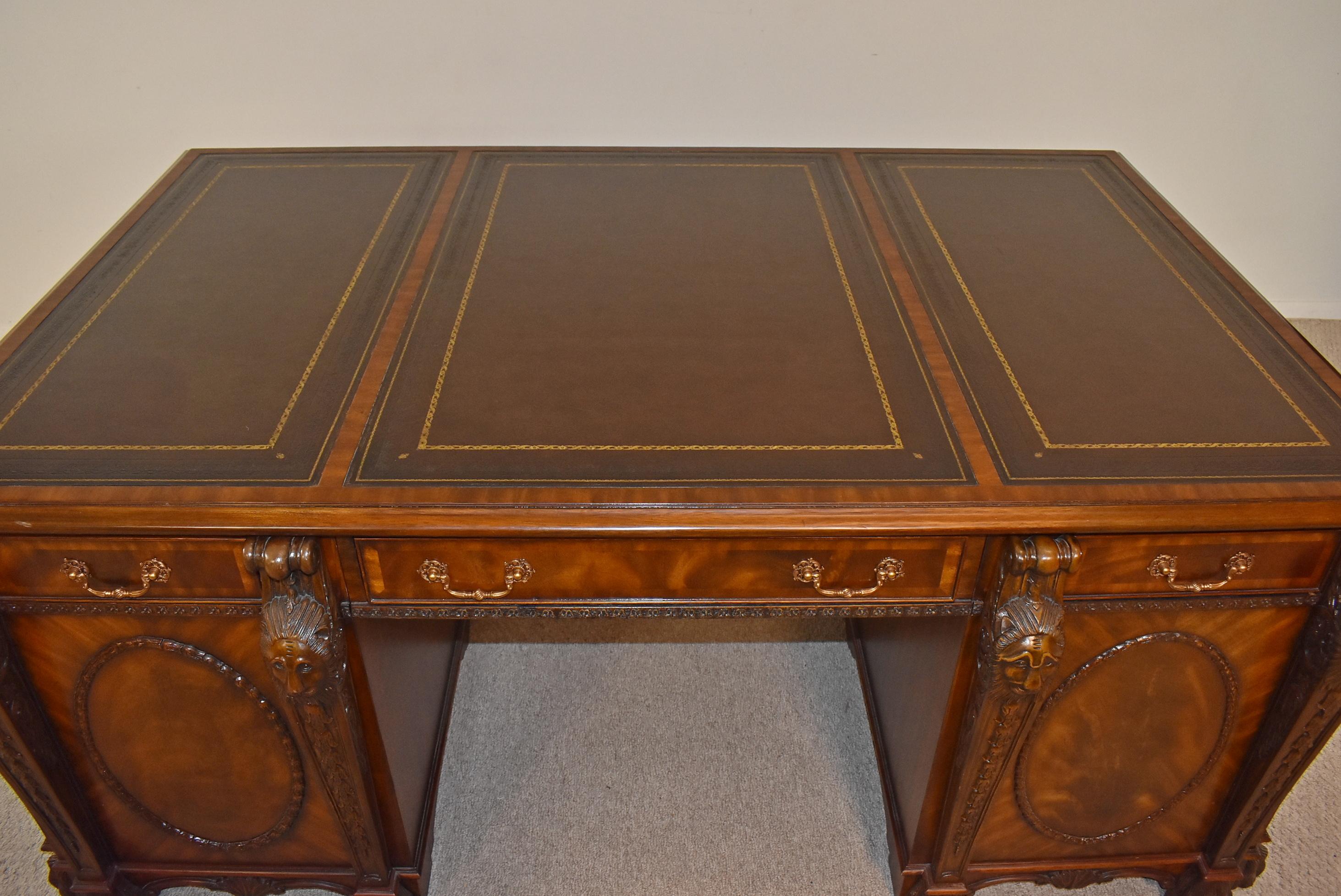 Chippendale Partners Desk by Maitland Smith. Circa 20th Century. Designed to evoke the refined decorative style of antique English furniture, the partners desk features large medallions, ornamental lion heads, and an ornate swag beneath the desk