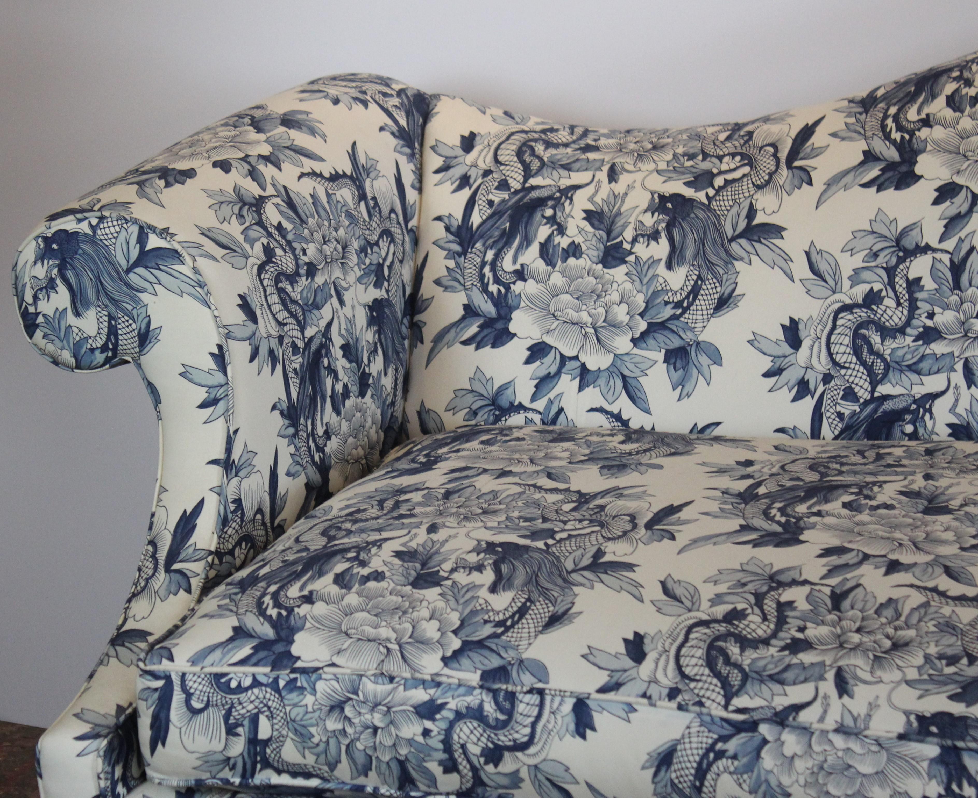 Chippendale style sofa with a camel-back form and a serpentine bow front edge. Features Ralph Lauren toile chinoiserie style blue and white upholstery with dragon and foliate detail. Sits on four tapered front legs with cross stretchers and four