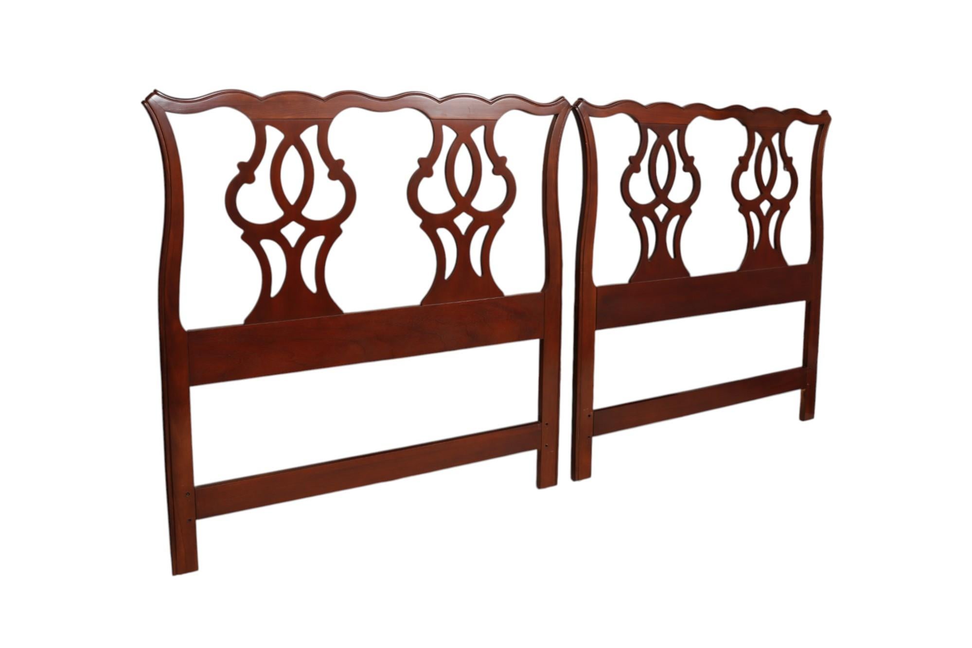 A pair of Chippendale style twin headboards made by Drexel Heritage Furnishings, Inc. Mahogany frames are carved with serpentine crest rails, and each have two pierced, chair back supports. Maker's label can be seen in the back, along with the