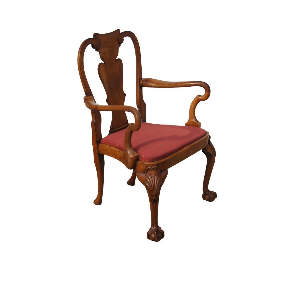 A Chippendale style armchair in walnut with a distressed finish and elaborately carved knees and ball and claw feet.