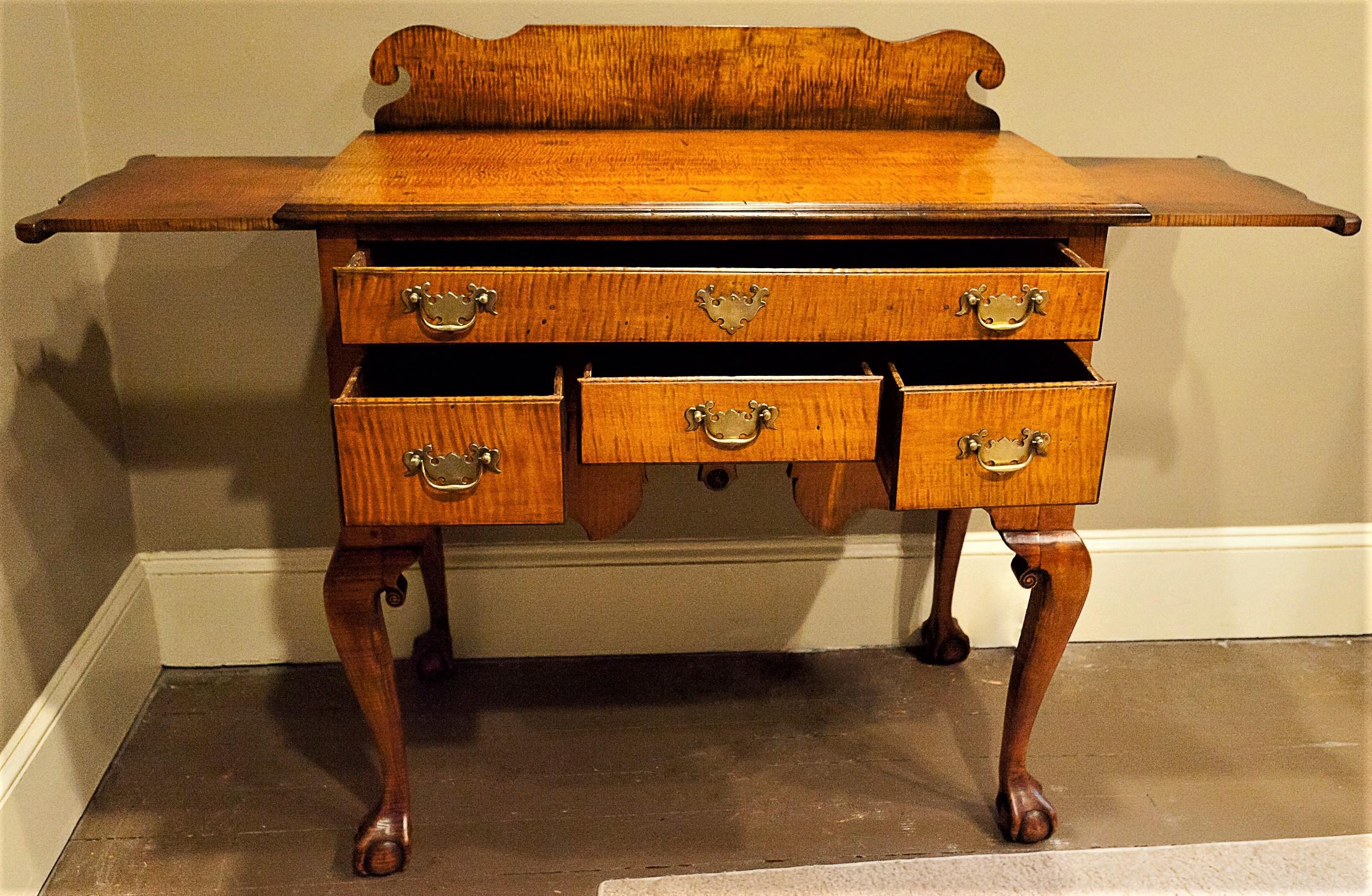 This piece was probably the bottom of a highboy originally. Around one hundred years ago it was adapted into a server with the addition of the matching tiger maple top, two pull out shelves, and back splash to become a very useful server. The lowboy