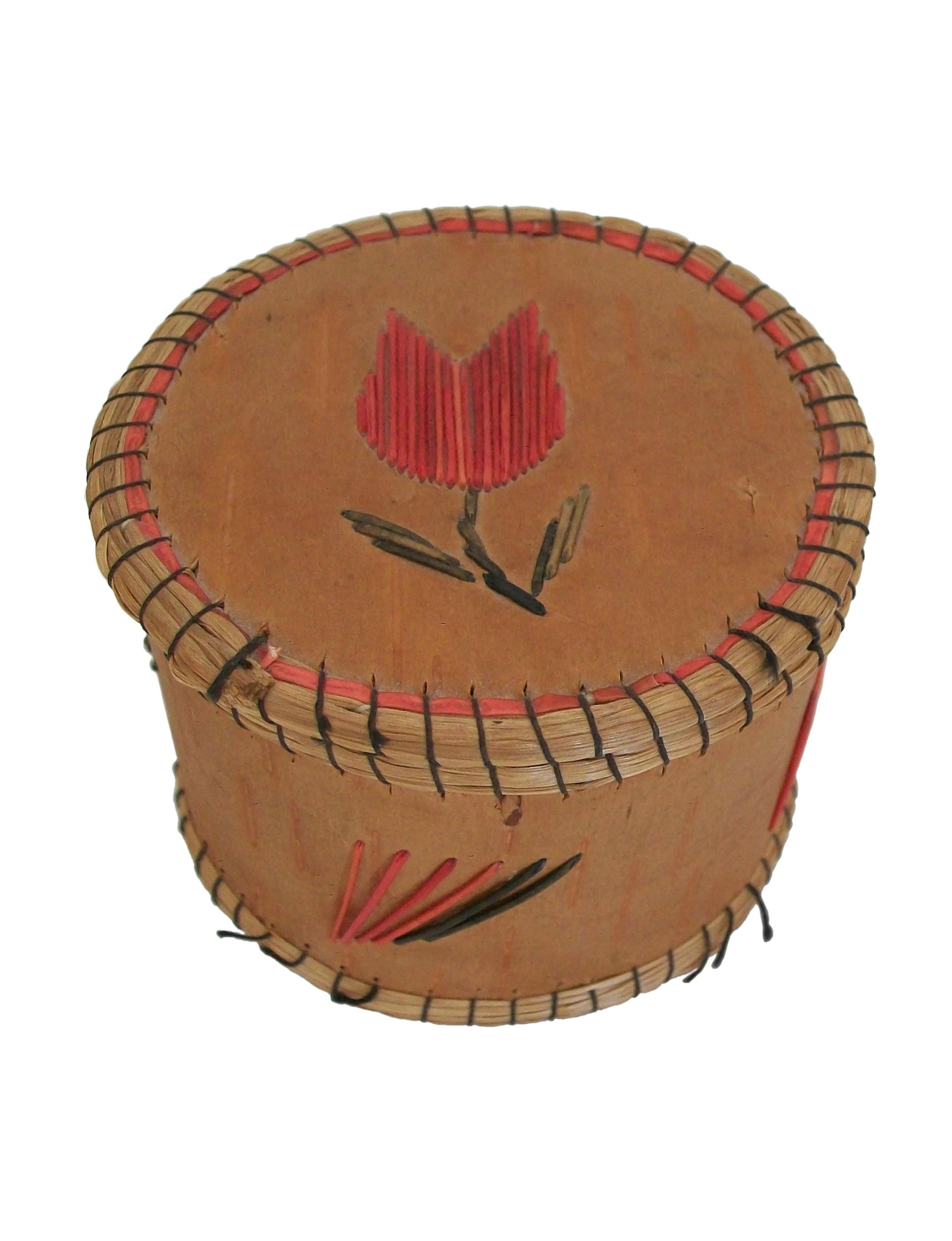 Boîte à couvercle en écorce de bouleau de style chippewa (également connu sous le nom d'Ojibwe), décorée de piquants de porc-épic et de bords en foin d'odeur fixés avec du fil noir. Elle présente une tulipe rouge finement piquée avec une tige et des