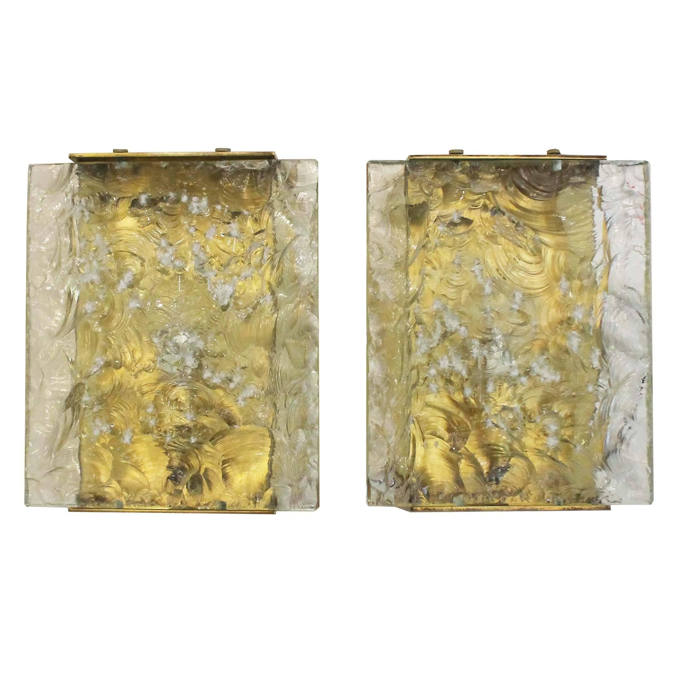 Eye catching sconces by Max Ingrand featuring hand chiseled glasses on a brass frame. On the side they are closed off by two cream colored glasses. Each holds one candelabra socket.