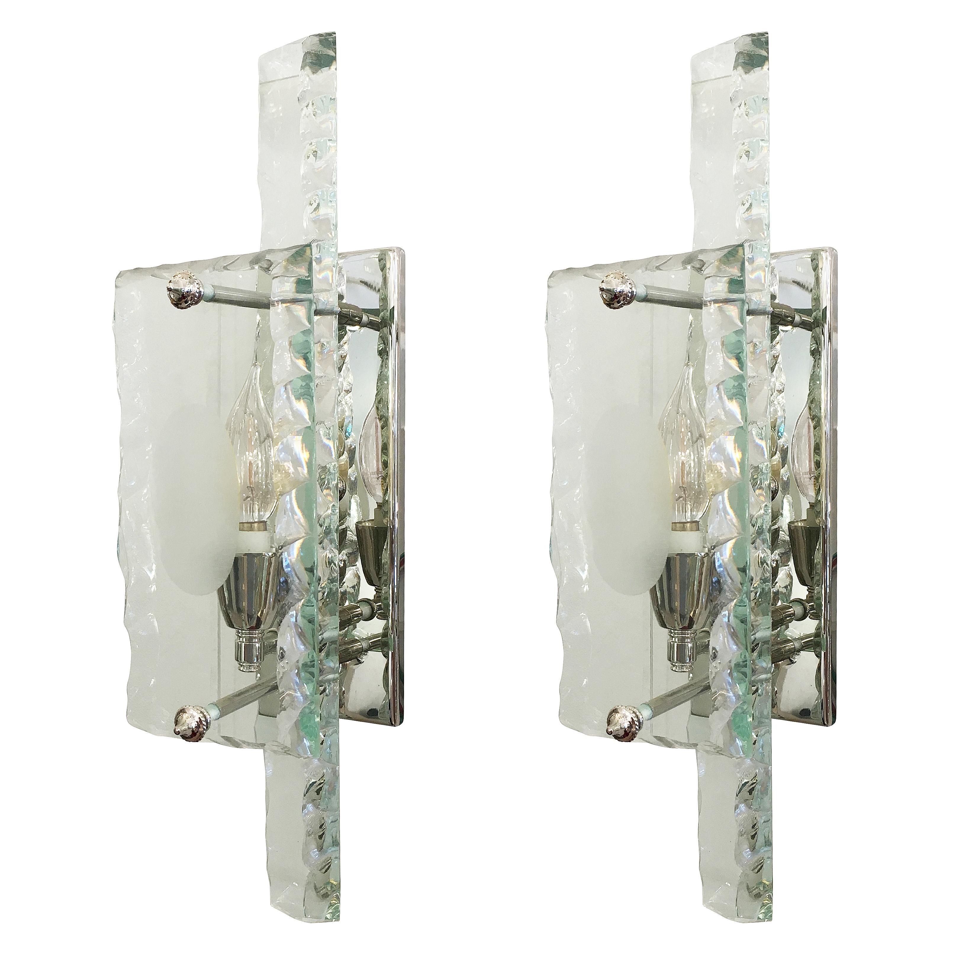 Sculptural set of Italian Mid-Century sconces by ZeroQuattro influenced by the designs of Fontana Arte. They feature two thick slabs of glass hand chiseled along the borders. The slab closer to the back plate is narrow and elongated while the front