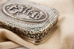 Chiseled silver city-allegory jewelry box with floral motifs and gold interior
