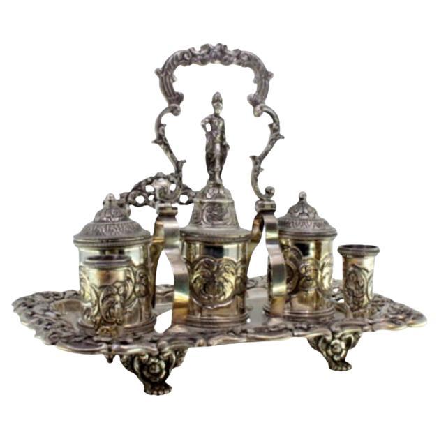 Chiseled silver inkwell with cut-out tray, three tanks, bell 
claw feet