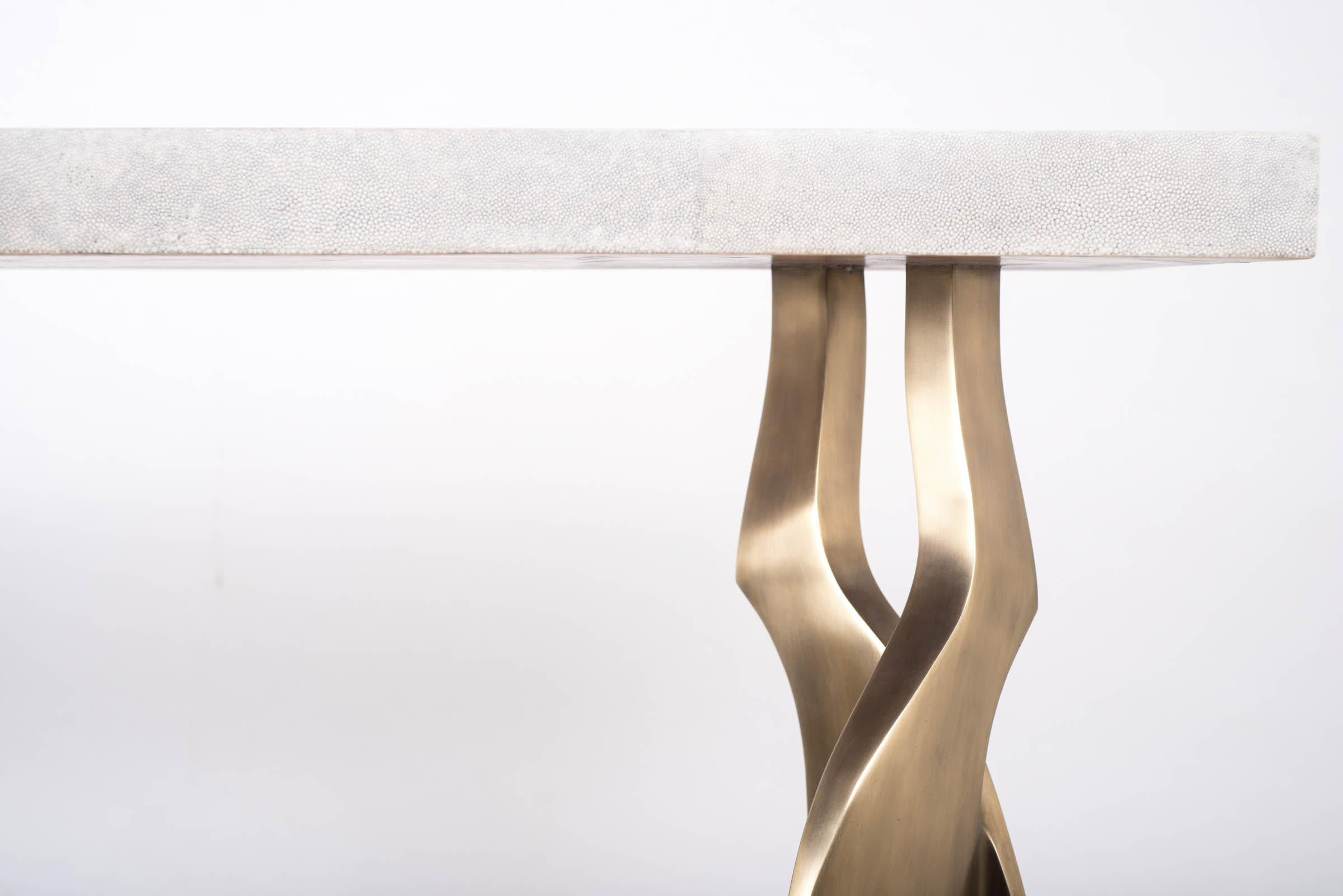 La table console Chital est à la fois spectaculaire et organique grâce à son design unique. Le plateau en marqueterie de galuchat crème repose sur une paire de pieds éthérés et sculpturaux en laiton bronze-patine. Cette pièce a été conçue par Kifu