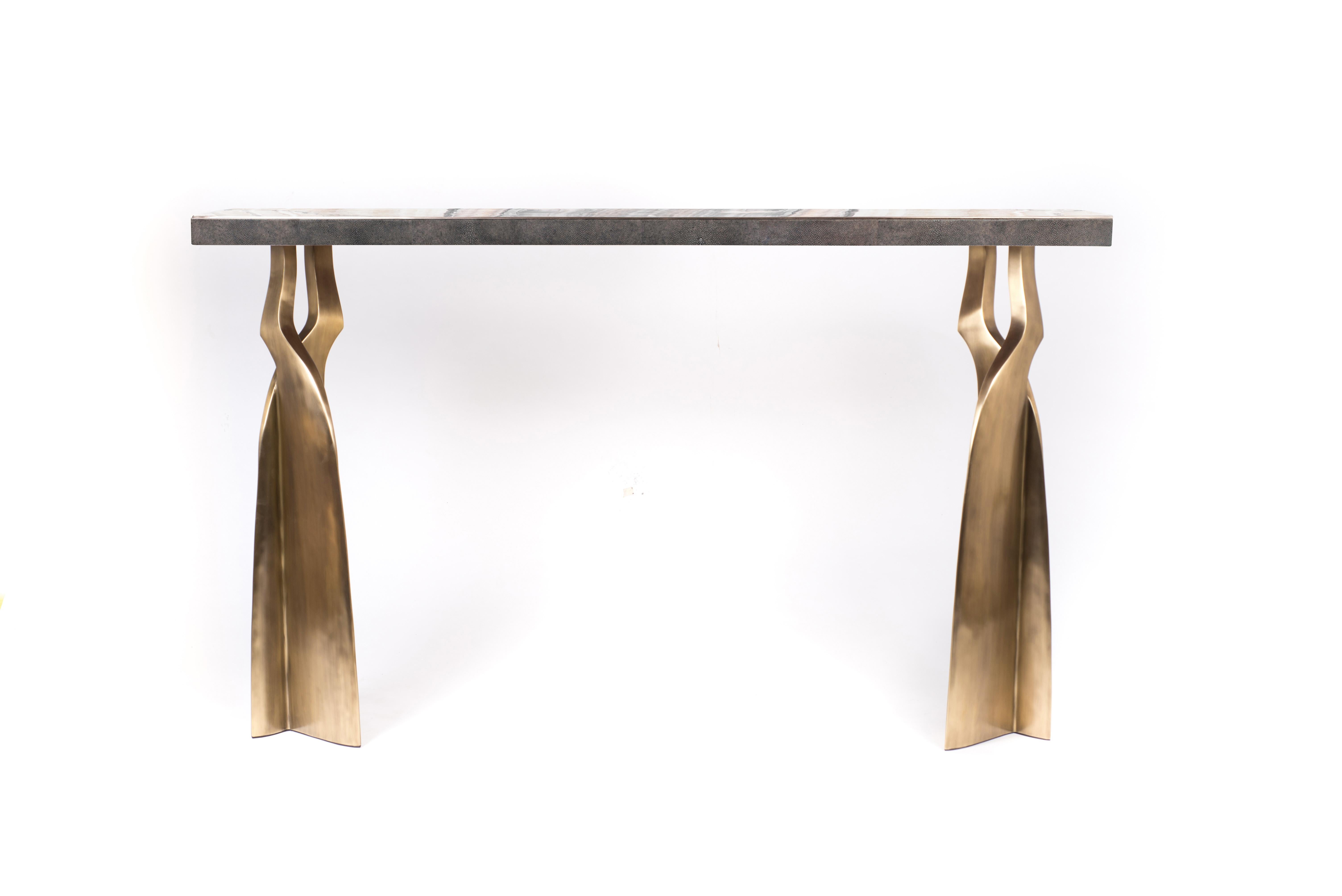 The Chital console table is both dramatic and organic it’s unique design. The onyx inlaid top, with its side borders inlaid in coal black shagreen, sits on a pair of ethereal and sculptural bronze-patina brass legs. This piece is designed by Kifu