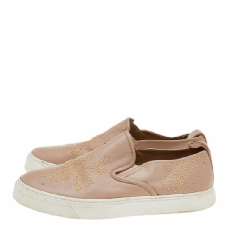 Ponte estas zapatillas de la Casa de Chloe y experimenta el estilo y la comodidad como nunca antes. Están confeccionadas en piel beige y presentan adornos en la parte superior, un estilo slip-on y plantillas forradas de piel. Son una gran elección