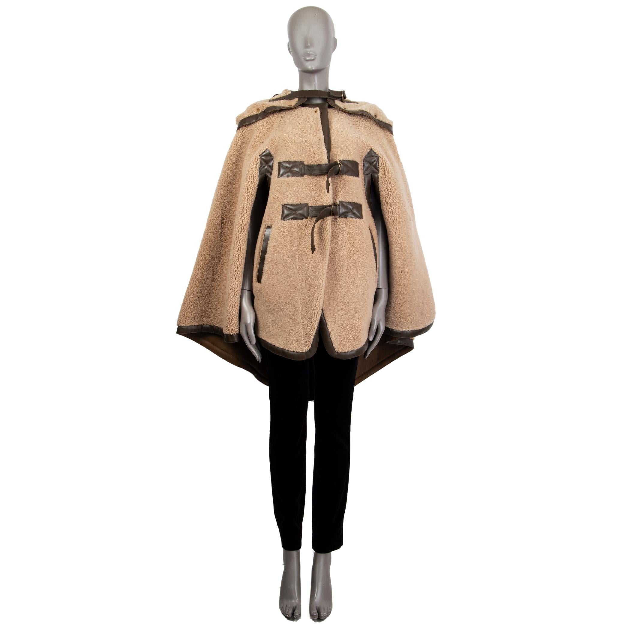 authentic Chloé cape in camel and olive green shearling with two slit pockets on the front. Has a detachable hood that can be worn over the shoulders. Its hood zipps open and has brass tone snap buttons. Closes on the front with two adjustable