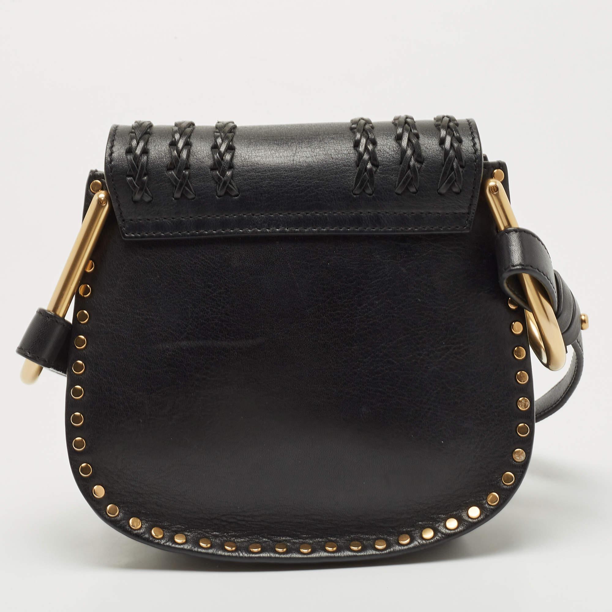 This Chloe Hudson bag exudes a fun, Boho-chic vibe making it perfect for those day outings with friends. It features a black leather exterior accented with braid and stitch detailing. It features a playful tassel, gold-tone studs along the edges,
