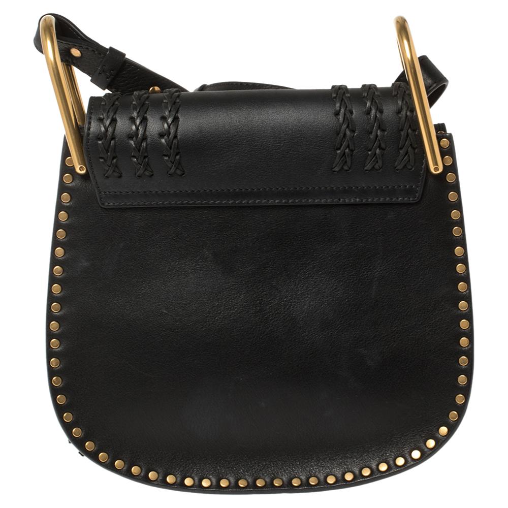 Der Hudson ist ein weiteres schönes und einzigartiges Design von Chloe. Diese stilvolle Tasche aus schwarzem Leder hat eine strukturierte Form mit geflochtenen Details auf der Klappe und goldfarbenen Nieten an der Außenseite:: die den Glamour dieser