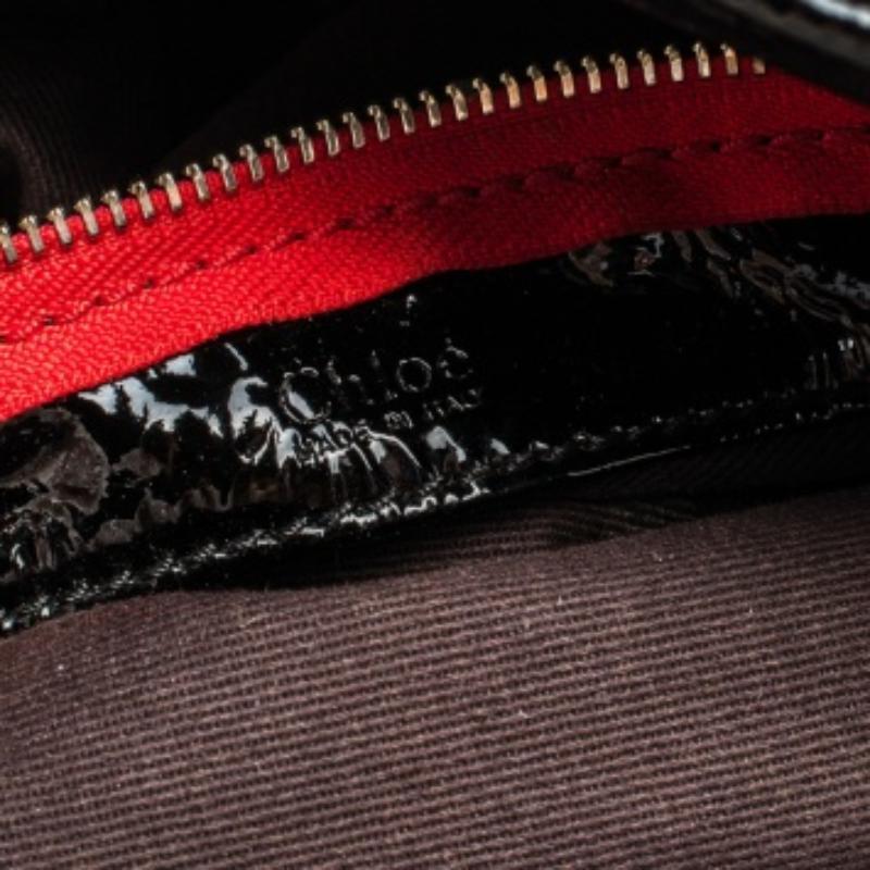 Ce sac à main Chloé en cuir noir verni est indispensable. Il présente des bordures en cuir contrasté et des poches plaquées à l'avant et à l'arrière. La bride est ornée de détails pyramidaux en cuir qui complètent les pieds pyramidaux vernis à la