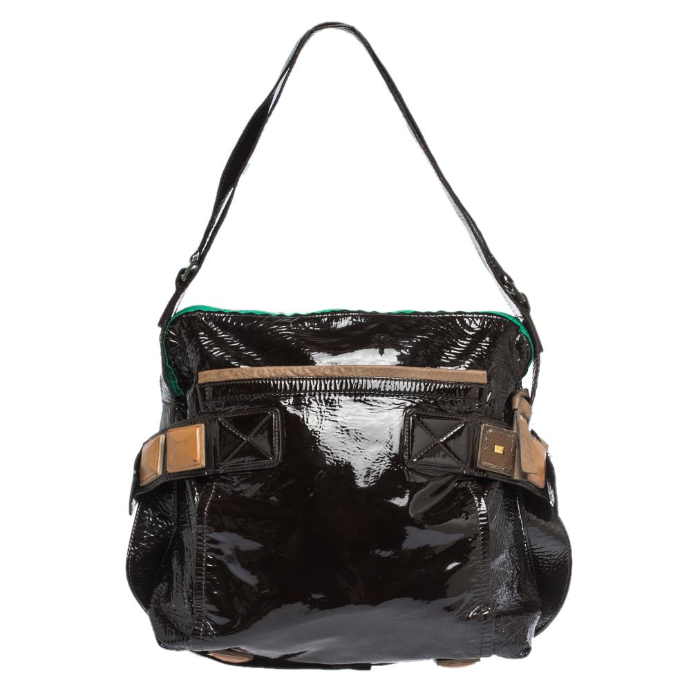 This Chloe handbag in patent black leather is a must-have. It features contrasting leather trims and front & back pockets. The bag has a single strap, leather pyramid detailing that complements the patent pyramid feet at the bottom. The interior is