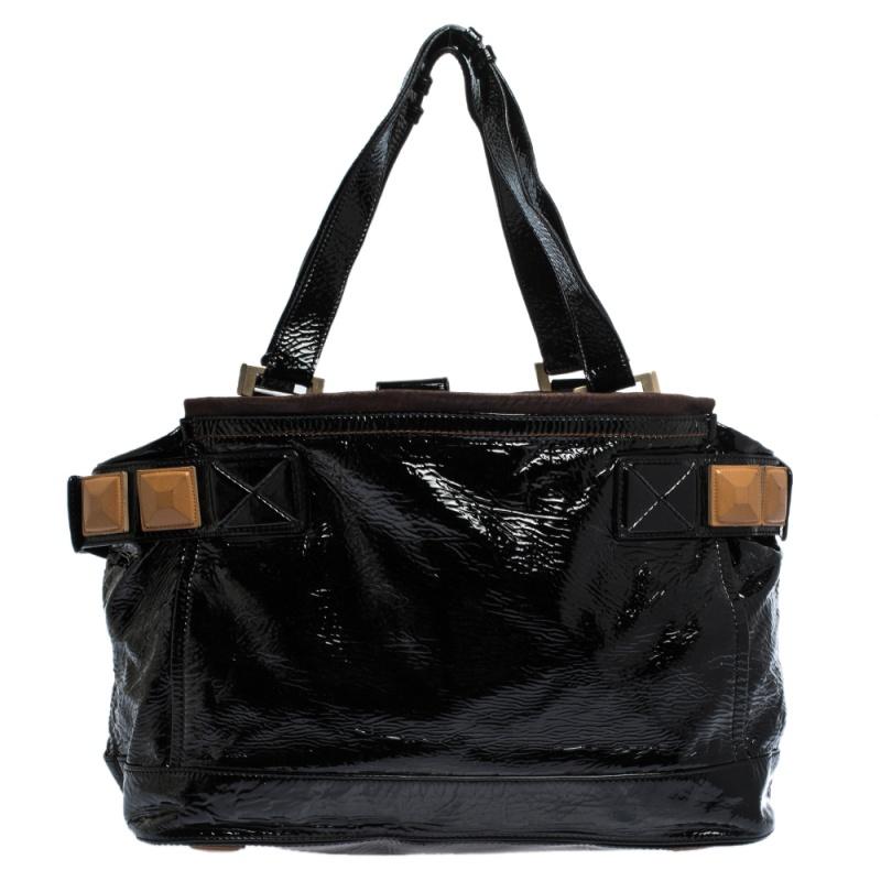 This Chloe handbag in patent black leather is a must-have. It features contrasting leather trims and front & back patch pockets. The strap bears leather pyramid detailing that complements the patent pyramid feet at the bottom. The interior is lined