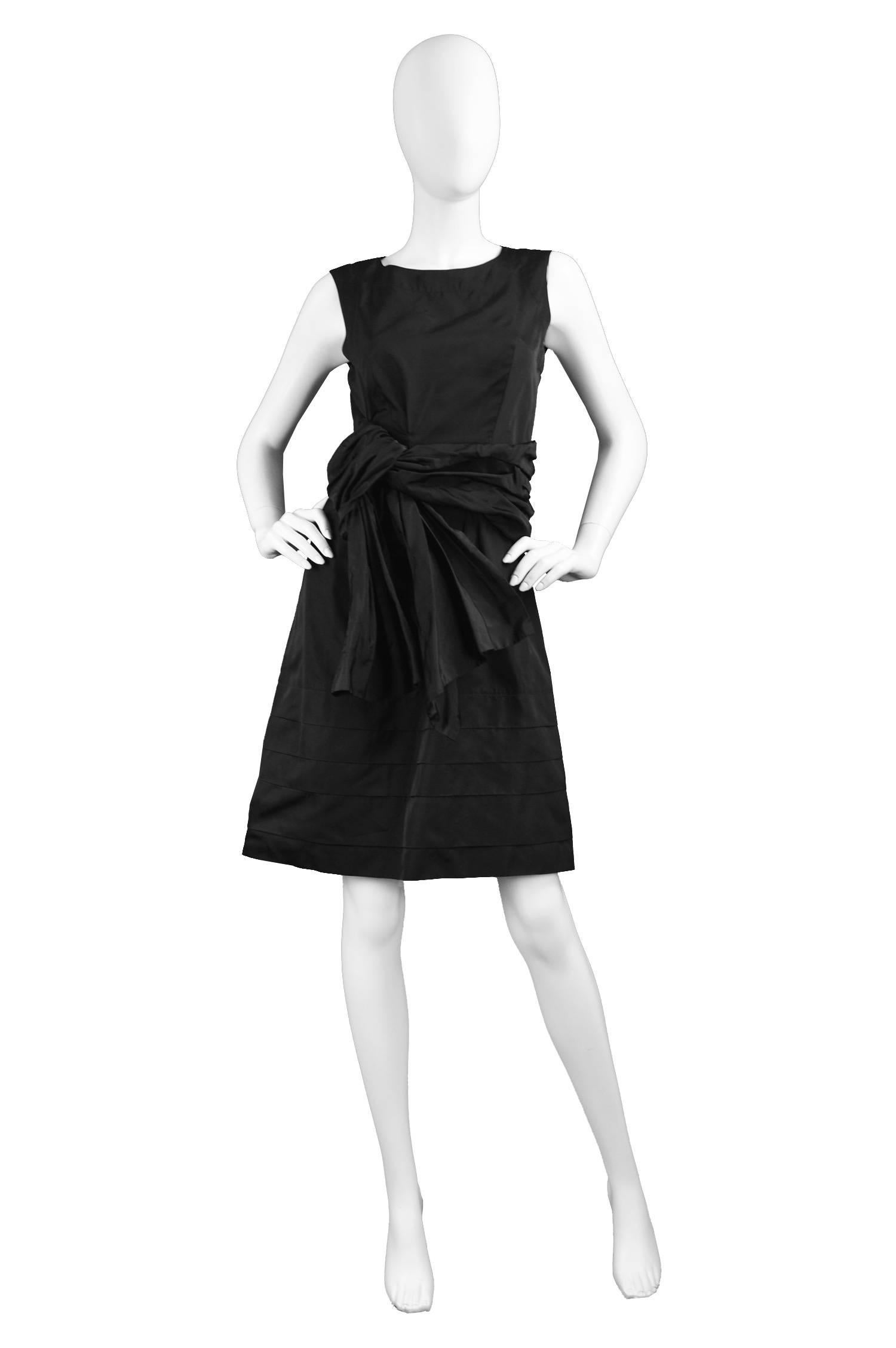 A chic sleeveless evening / party dress by Chloé. In a black 100% silk taffeta which gives incredible sheen and a tiered skirt. With a draped / soft pleated detail at the waist which looks like a nonchalantly deconstructed bow. 

Size: Label states