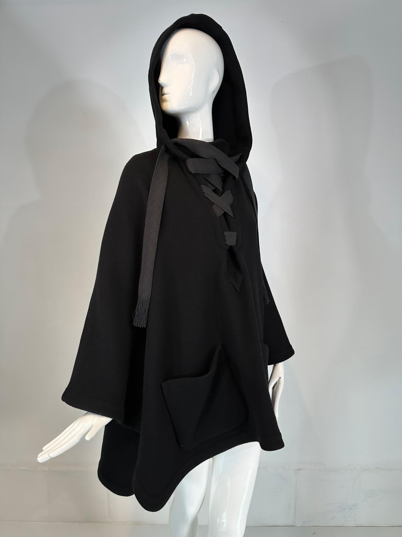 Unworn with tags. Chloe black wool flat woven black ribbon closure at the neck. The cape/poncho slips over the head there is an attached hood. There is a deep v gusset at the neck that closes with the ribbon. Two large patch pockets at the lower