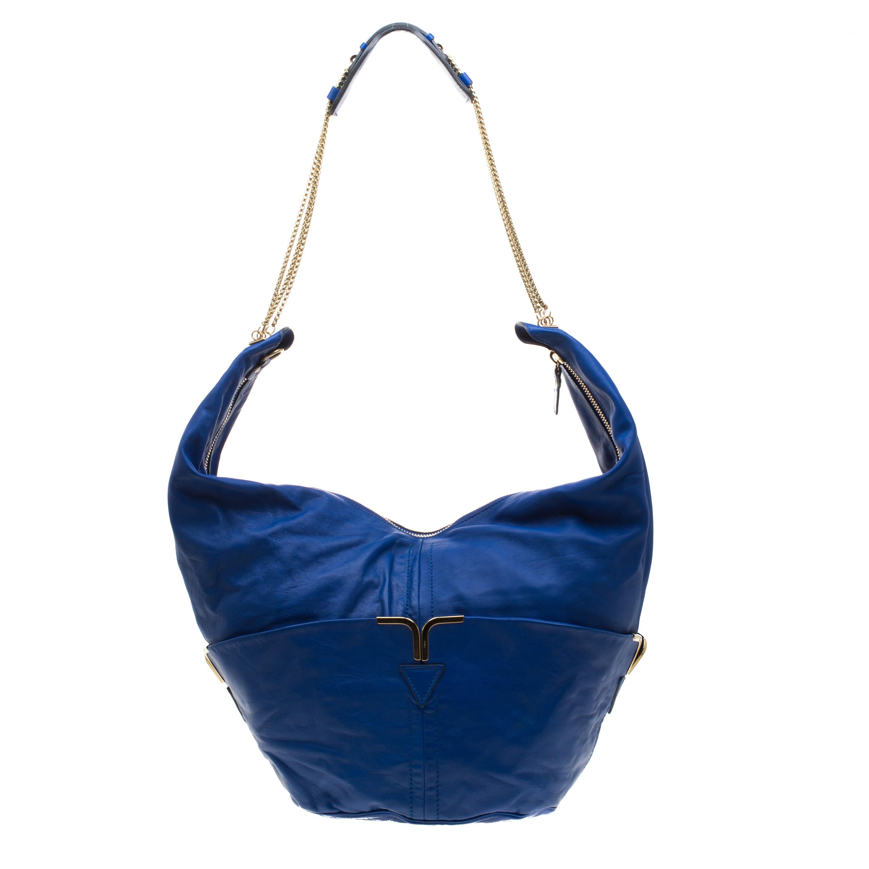 Update your bag collection with this Chloe Milton hobo. Crafted from a durable leather body in a gorgeous blue hue, this bag features a top zipper closure and comes equipped with two large pockets on the front and rear. Accented with gold-tone