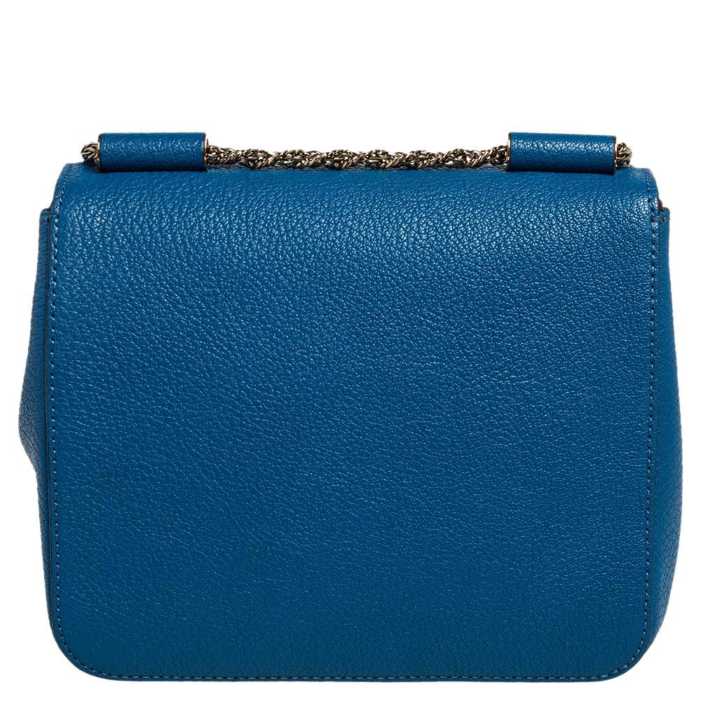 Die Elsie ist ein Klassiker von Chloé. Wir haben hier die Elsie Umhängetasche aus blauem Leder und goldfarbener Hardware. Die Tasche wird durch einen Drehverschluss an der Klappe gesichert und ist mit einem geräumigen Innenraum und einer