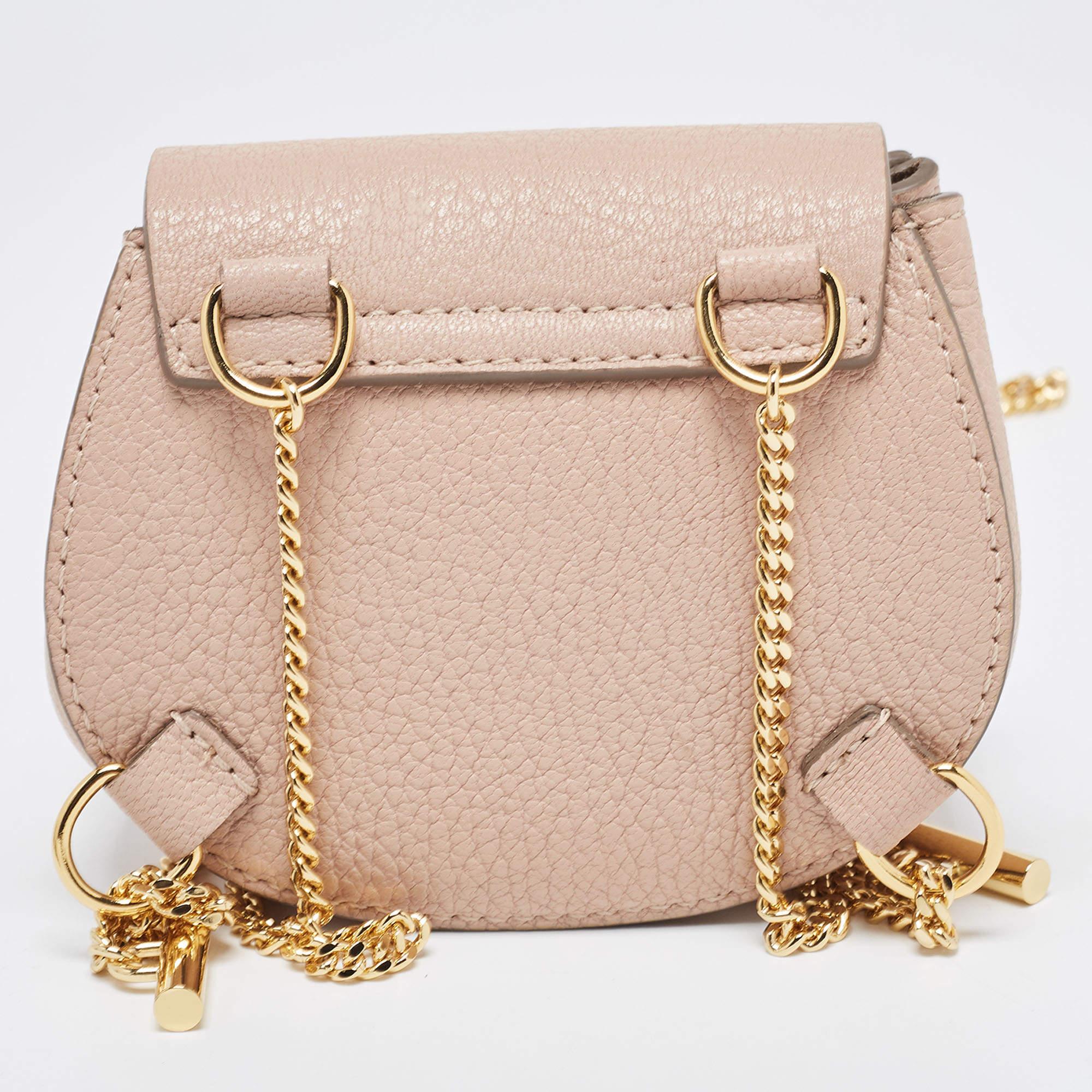 The Chloé Drew Backpack is a chic and compact accessory. Crafted from soft blush pink leather, it features a stylish flap closure with a gold-tone turn-lock clasp, shoulder straps, and a petite yet functional size perfect for carrying essentials in