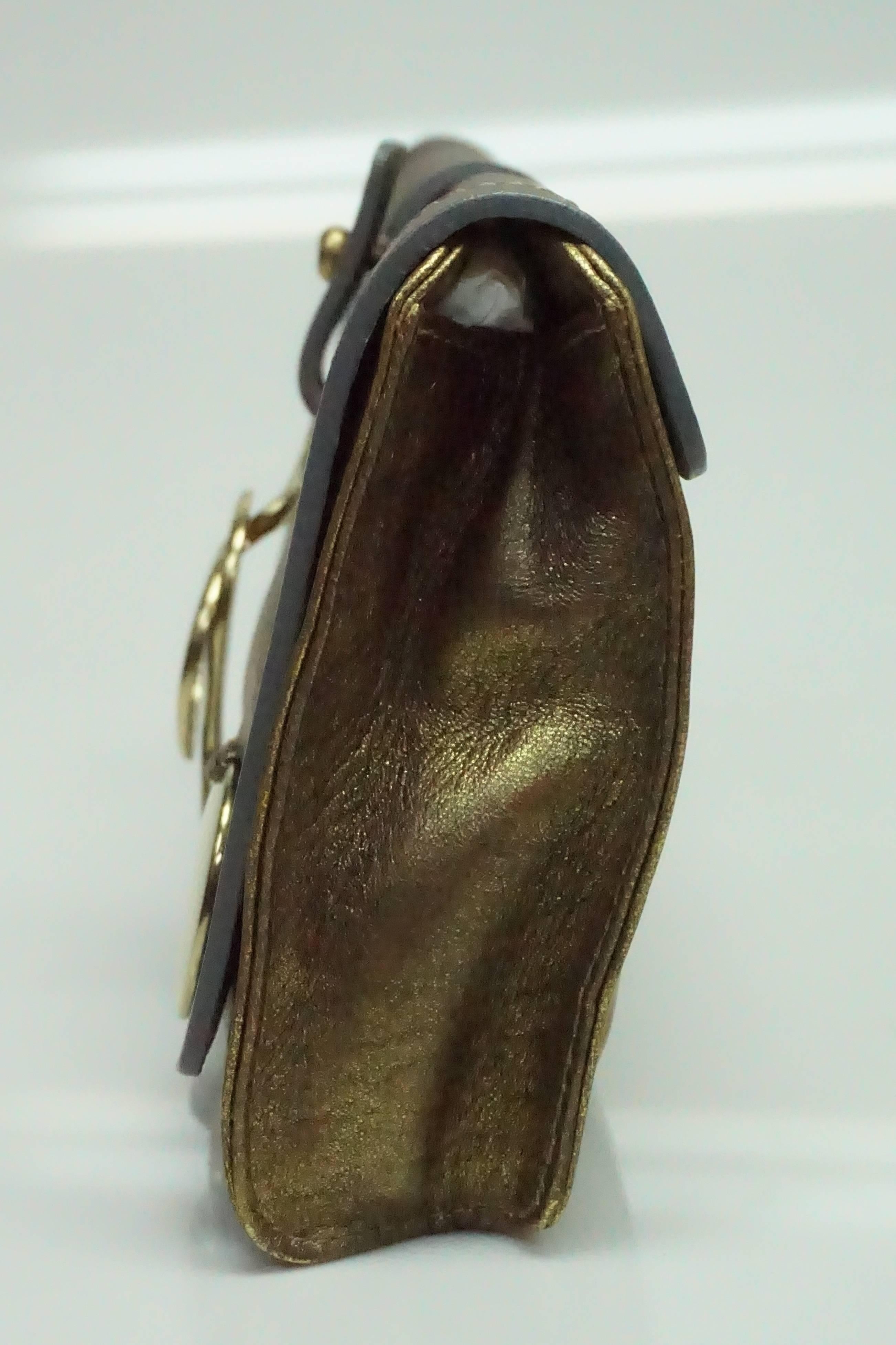 Chloe Bronze Metallic Clutch. This fabulous clutch is in good condition. There are few scratches and smudges on the gold hardware. It has a single flap and buckle opening. The clutch is made of soft leather and has two coin-like plates on the front.