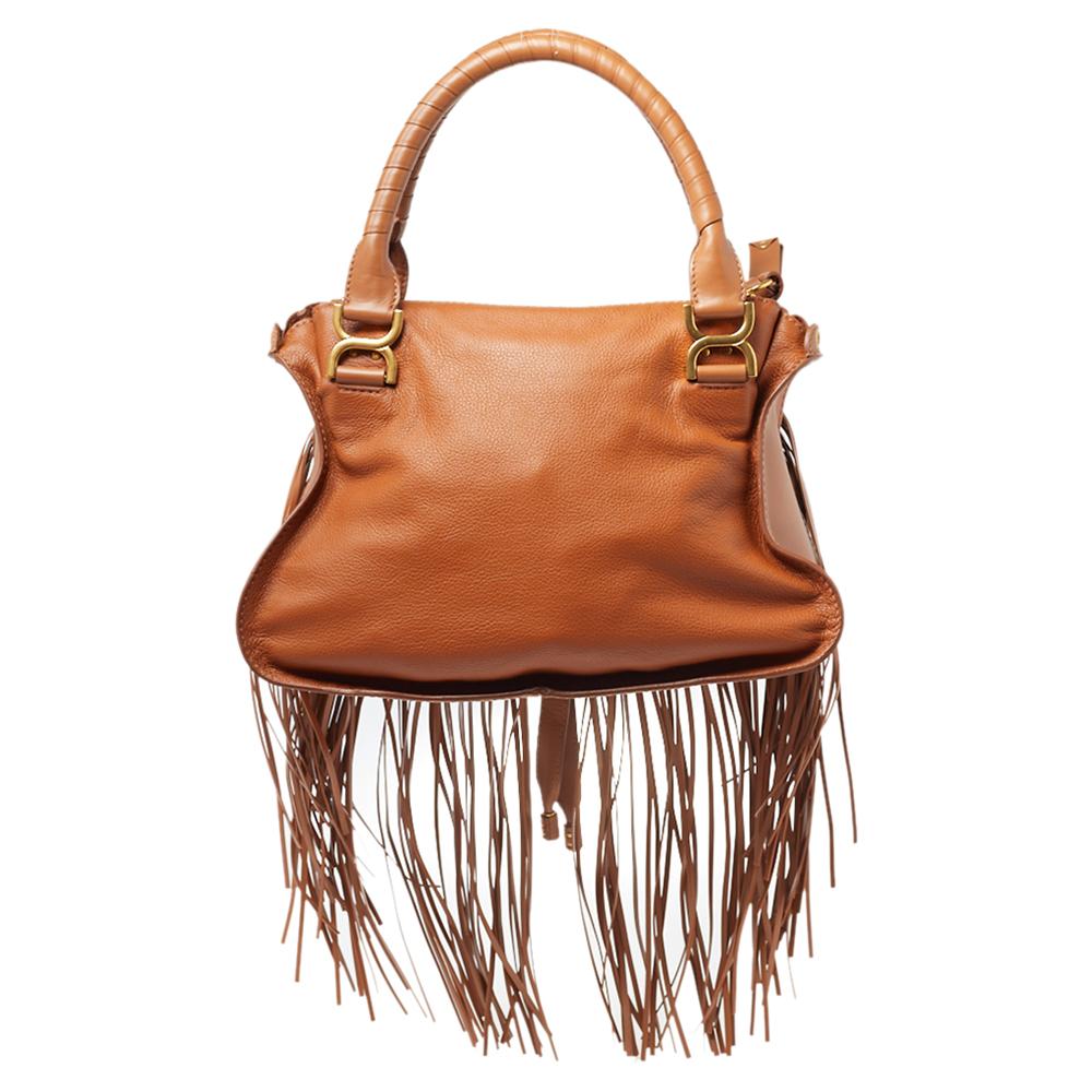 Stunning to look at and durable enough to accompany you wherever you go, this Chloe satchel is a joy to own! This Marcie bag is crafted from leather with dual handles and a well-designed front exterior enhanced with stitch detailing, a fringe, and