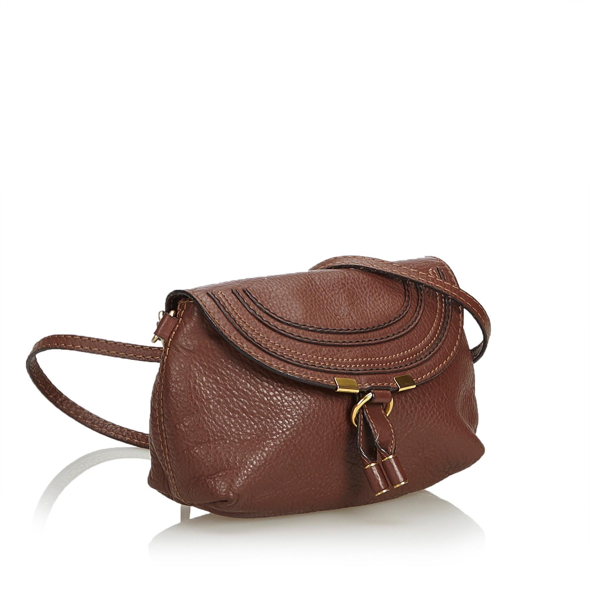 This Marcie crossbody bag features a leather body, a flat strap, a top flap with loop closure, and an interior slip pocket. It carries as B+ condition rating.

Inclusions: 
This item does not come with inclusions.

Dimensions:
Length: 13.00