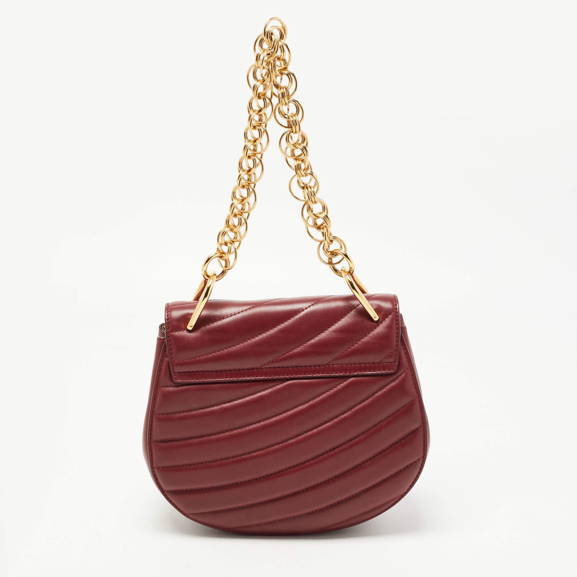 With its classic appeal and artistic design, this Chloe bag will win your heart at first sight. The gold-tone accents and the attractive patterns on the exterior of this burgundy creation make it a standout piece in your closet. Created from