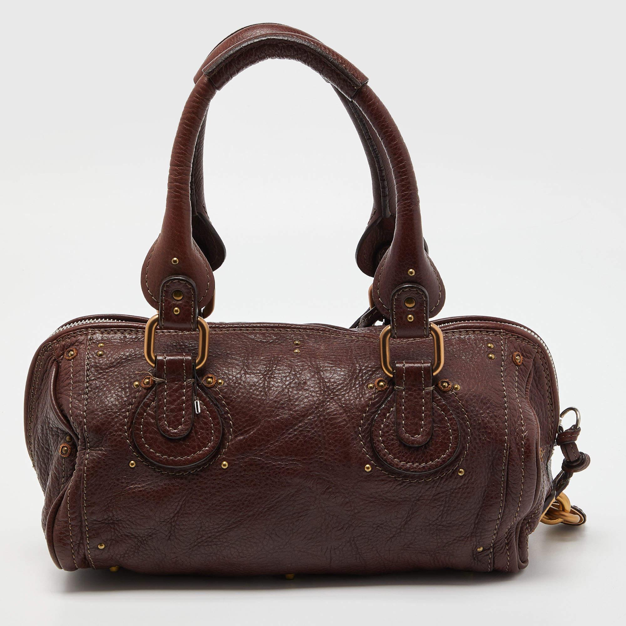 Chole’s Paddington bag is glamorous indeed with a retro vibe with two-tone metal accents. Crafted from burgundy leather, the interior is quite roomy and can house all your essentials. The bag features dual handles and is perfect for everyday