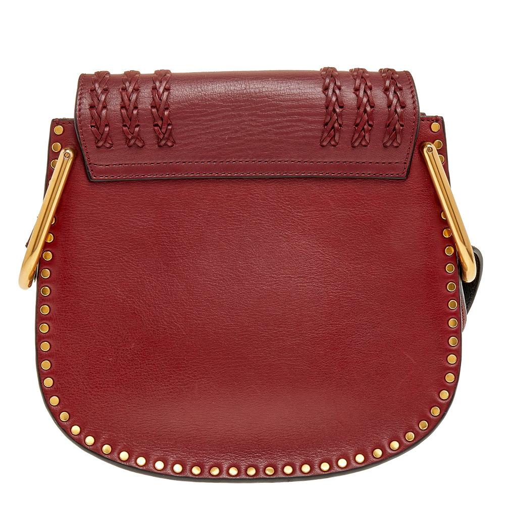 The Hudson is another one of Chloe's beautiful and unique designs. Crafted in burgundy leather, this stylish bag features a structured shape with braided detailing on the flap and gold-tone studs along the exterior to add to the glamour of this