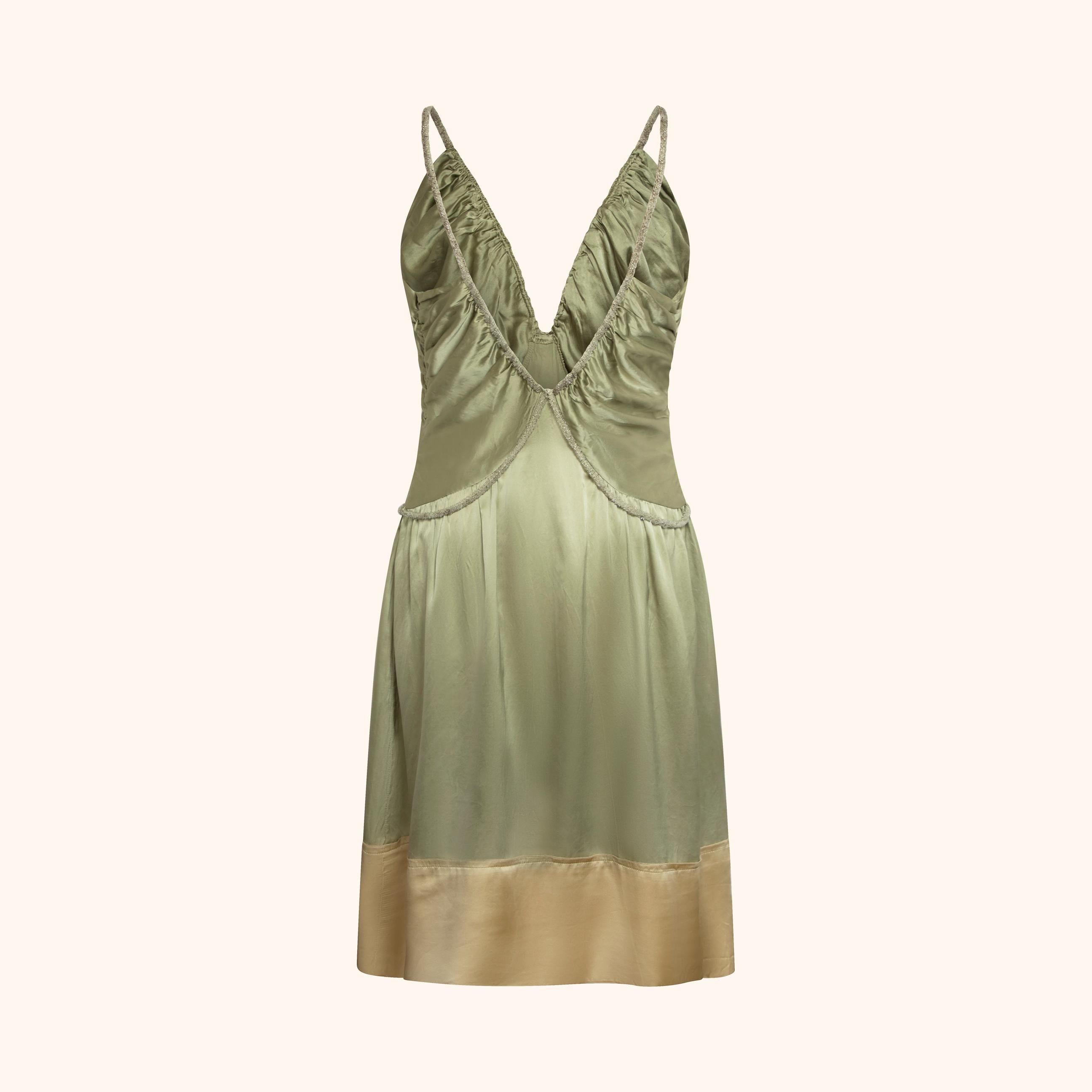 Laufstegteil aus der Frühjahr/Sommer-Kollektion 2005 von Phoebe Philo, gefertigt aus fließender olivgrüner Seide mit dezenten goldenen Untertönen.
Mit tiefem Dekolleté, gerafftem Brustausschnitt und dem charakteristischen Metallic-Lurex-Kordelzug,