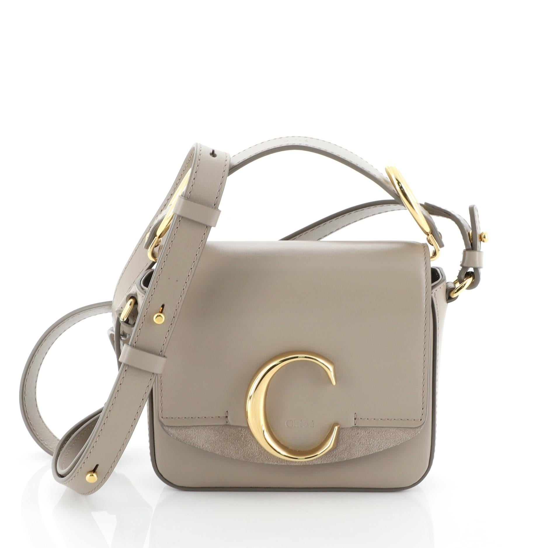 This Chloe C Crossbody Bag Leather Mini, crafted in neutral leather, features a leather top handle, C logo on flap, and gold-tone hardware. Its push-lock closure opens to a neutral fabric interior with slip pocket.

Condition: Very good. Odor in