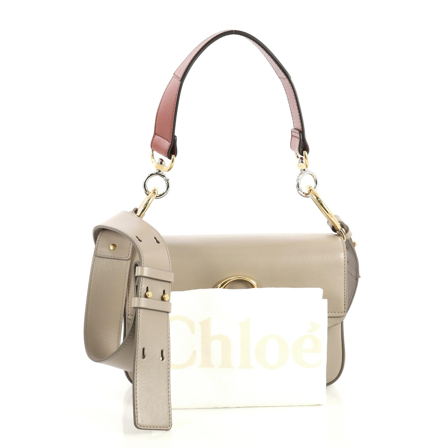 This Chloe C Double Carry Bag Leather Small, crafted in beige leather, features a flat leather strap, C logo on flap, and gold-tone hardware. Its push-lock closure opens to a neutral canvas interior with zip pocket. 

Estimated Retail Price: