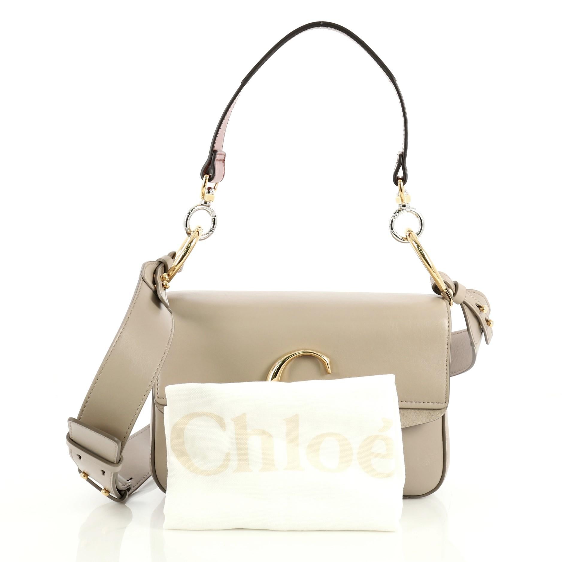 This Chloe C Double Carry Bag Leather Small, crafted in neutral leather, features a flat leather strap, C logo on flap, and gold-tone hardware. Its push-lock closure opens to a neutral canvas interior with zip pocket. 

Estimated Retail Price:
