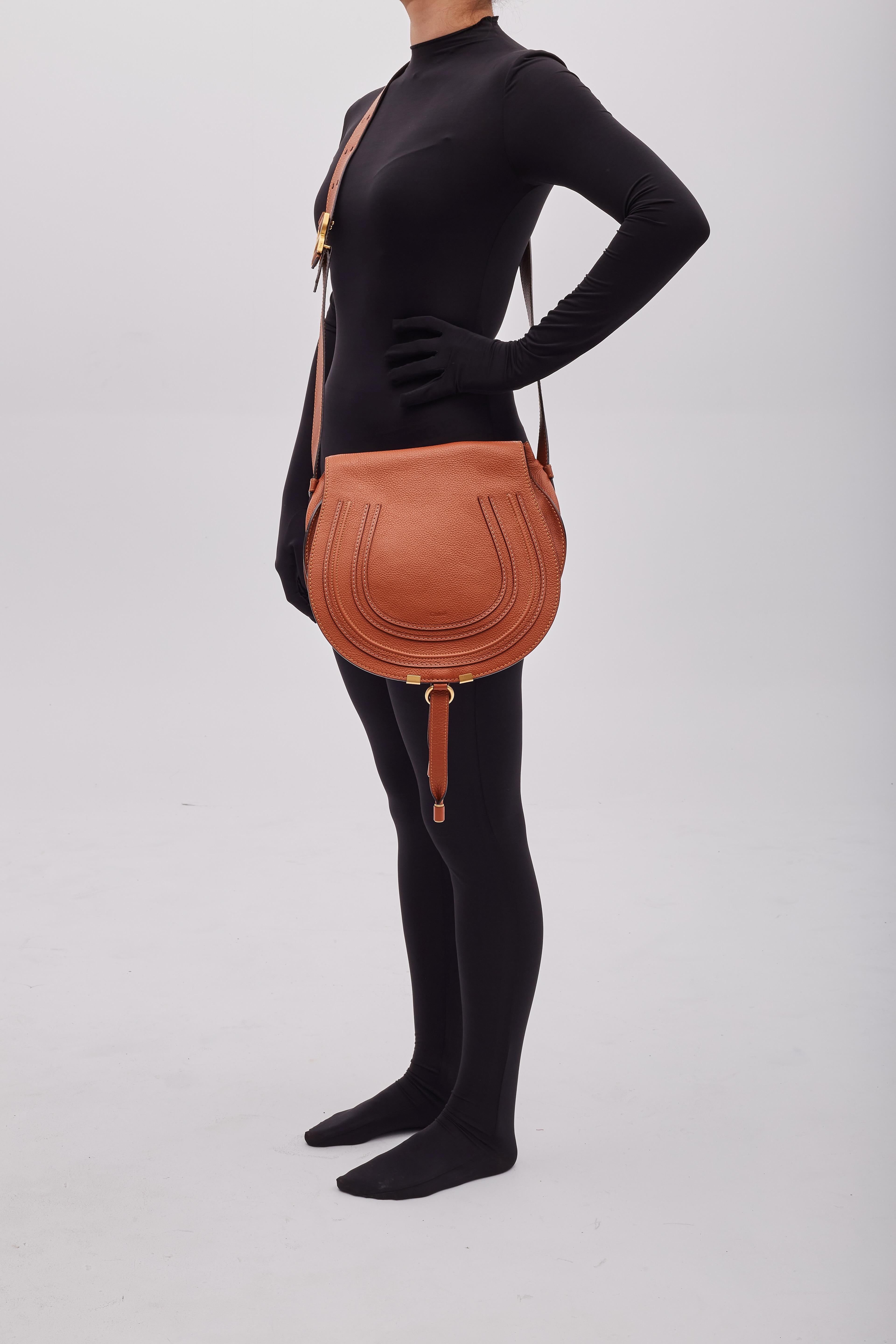 This stylish hobo is bag is made of grained textured calfskin leather in cognac brown /caramel. The bag features an adjustable crossbody strap, a facing flap with detailed stitching, a front tassel an antiqued gold tone hardware. The flap opens to a