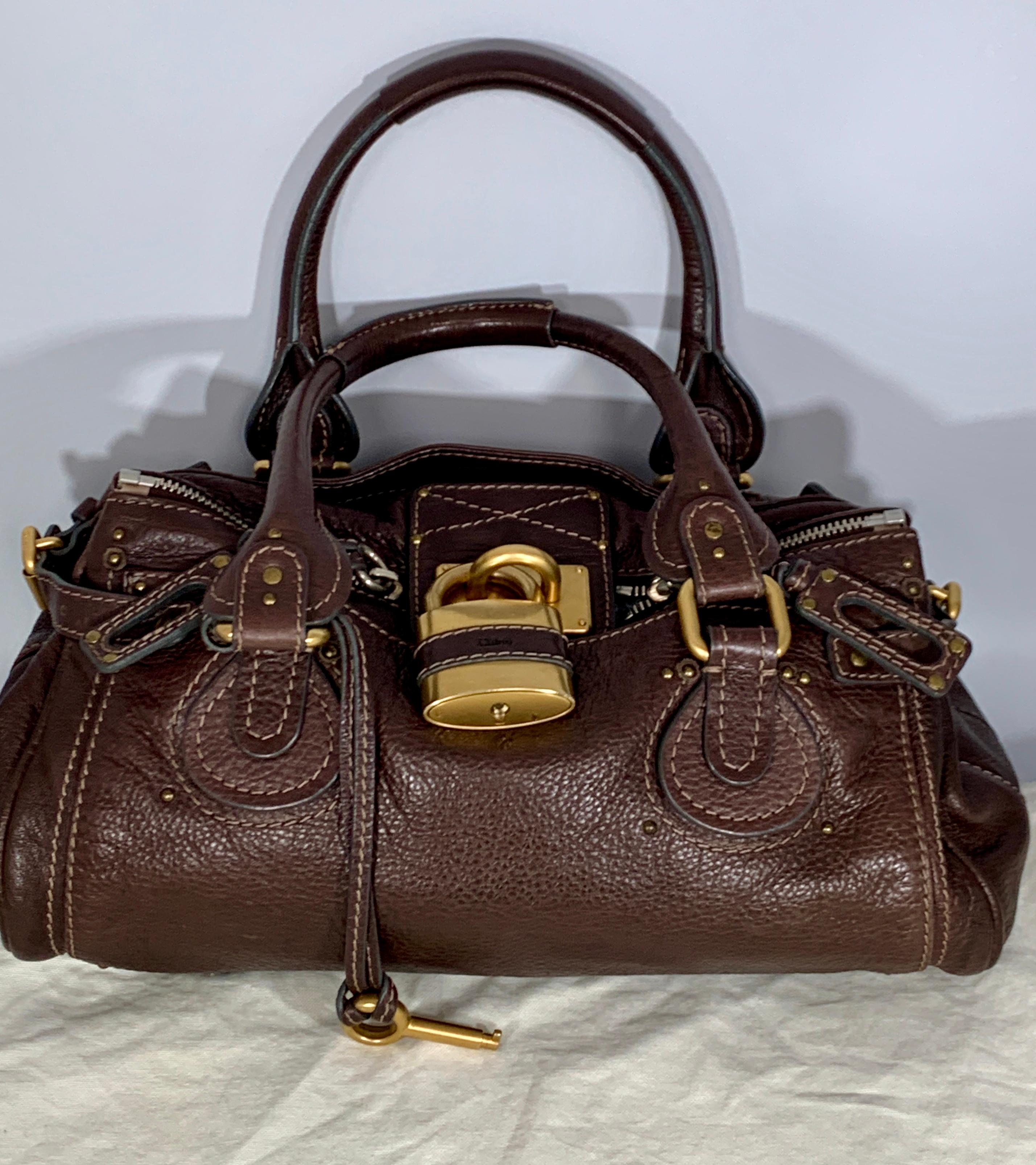 Get the bag that is coveted by celebrities everywhere! This gorgeous Chloe Paddington Medium Satchel Bag in this rich dark brown color. It has a slouchy rectangular shape that is ultra-spacious and features incredible details such as a giant Chloe