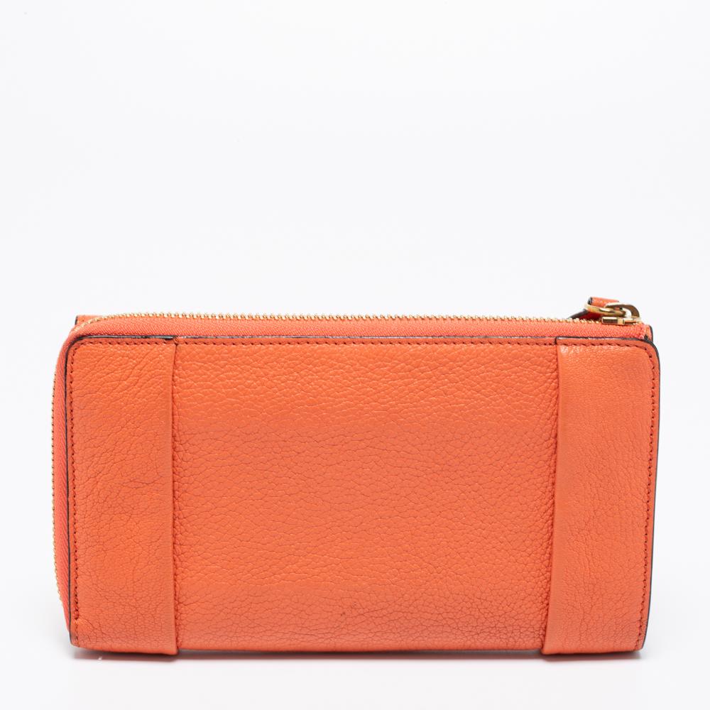 Every curve and detail on this Chloe Elsie is grand, which adds to the worth of the wallet. It has been crafted from leather and styled with a flap. The coral orange wallet is secured by a lock and a zip closure revealing a well-sized interior. The