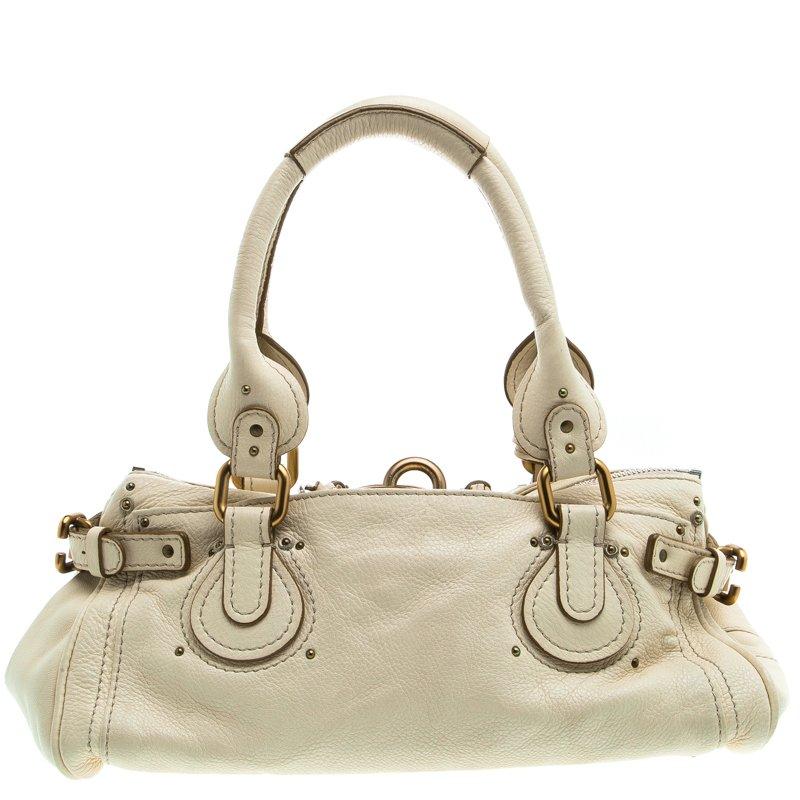 This satchel from Chloe is simple yet stylish in its design. Crafted from cream leather, it is equipped with two top handles, buckle details on the sides and protective metal feet at the bottom. The satchel has a lock and key at the front and the