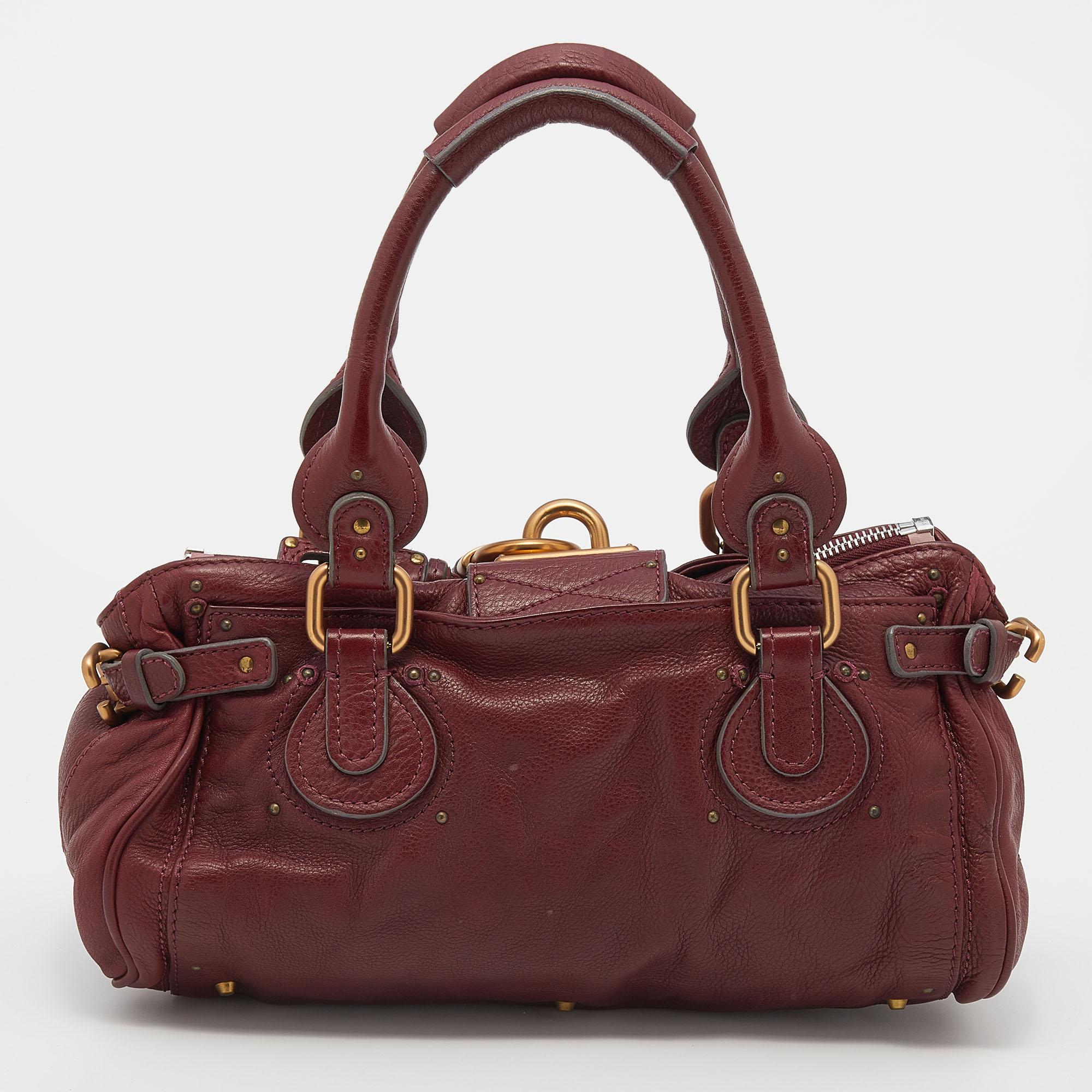 Diese Chloe Paddington Schultertasche unterstützt Ihren tadellosen Stil an allen Tagen. Goldfarbene Beschläge mit einem klobigen Schloss auf der Vorderseite ziehen leicht alle Blicke auf sich. Das purpurrote Leder hat eine interessante Textur,