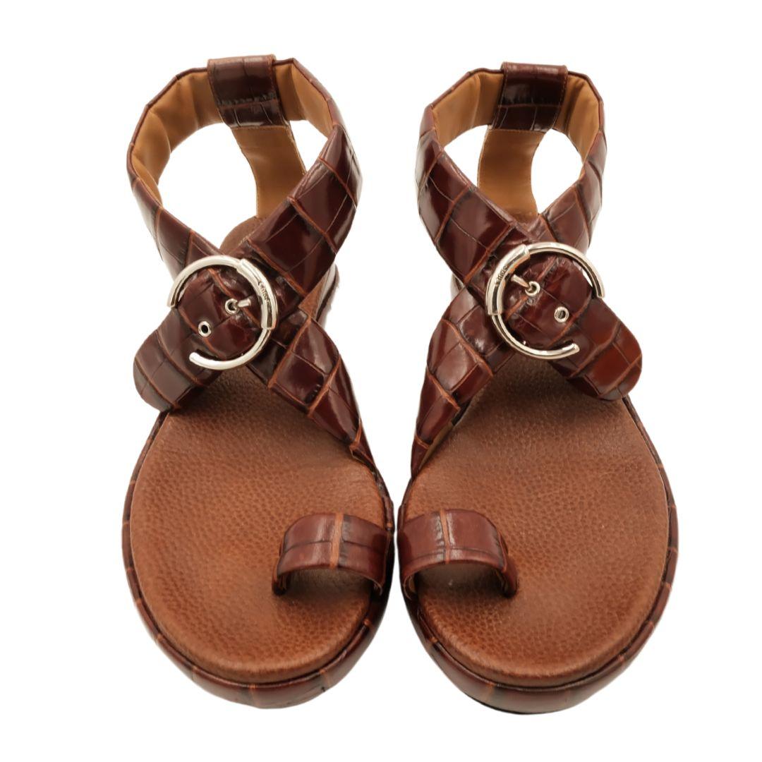 Chloe brown croc embossed patent leather flat sandals with thick buckle ankle straps and toe loop. Chunky circular silver hardware with logo detail.

Condition Details: Very good preowned condition. Minor scuffs and marks at soles. Refer to photos