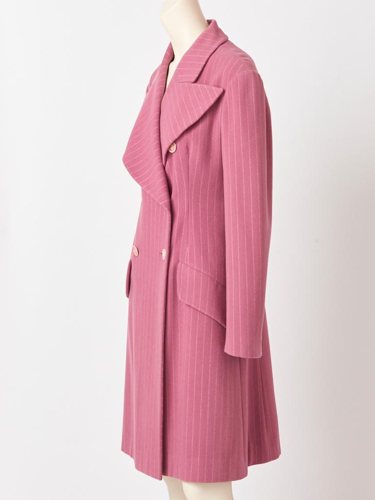 Chloe, mauve tone, wool, pin stripe, fitted, double breasted coat, having an exaggerated, wide lapel collar, and slanted, flap pocket detail. Back of coat has a half belt and a middle open vent. Interior is lined in a soft mauve silk.  Designed by